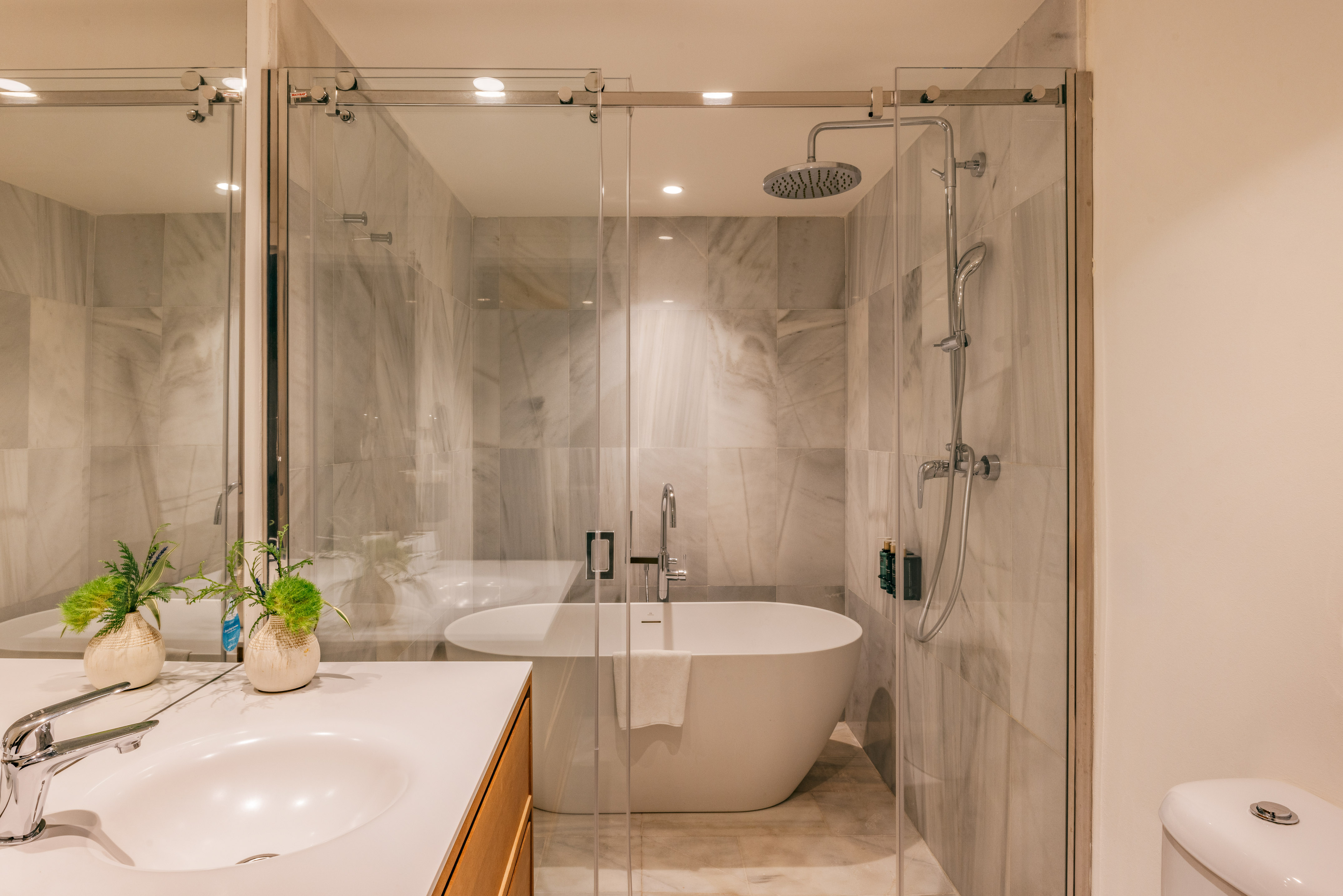Modern bathroom with marble shower, freestanding tub, glass enclosure, and vanity.