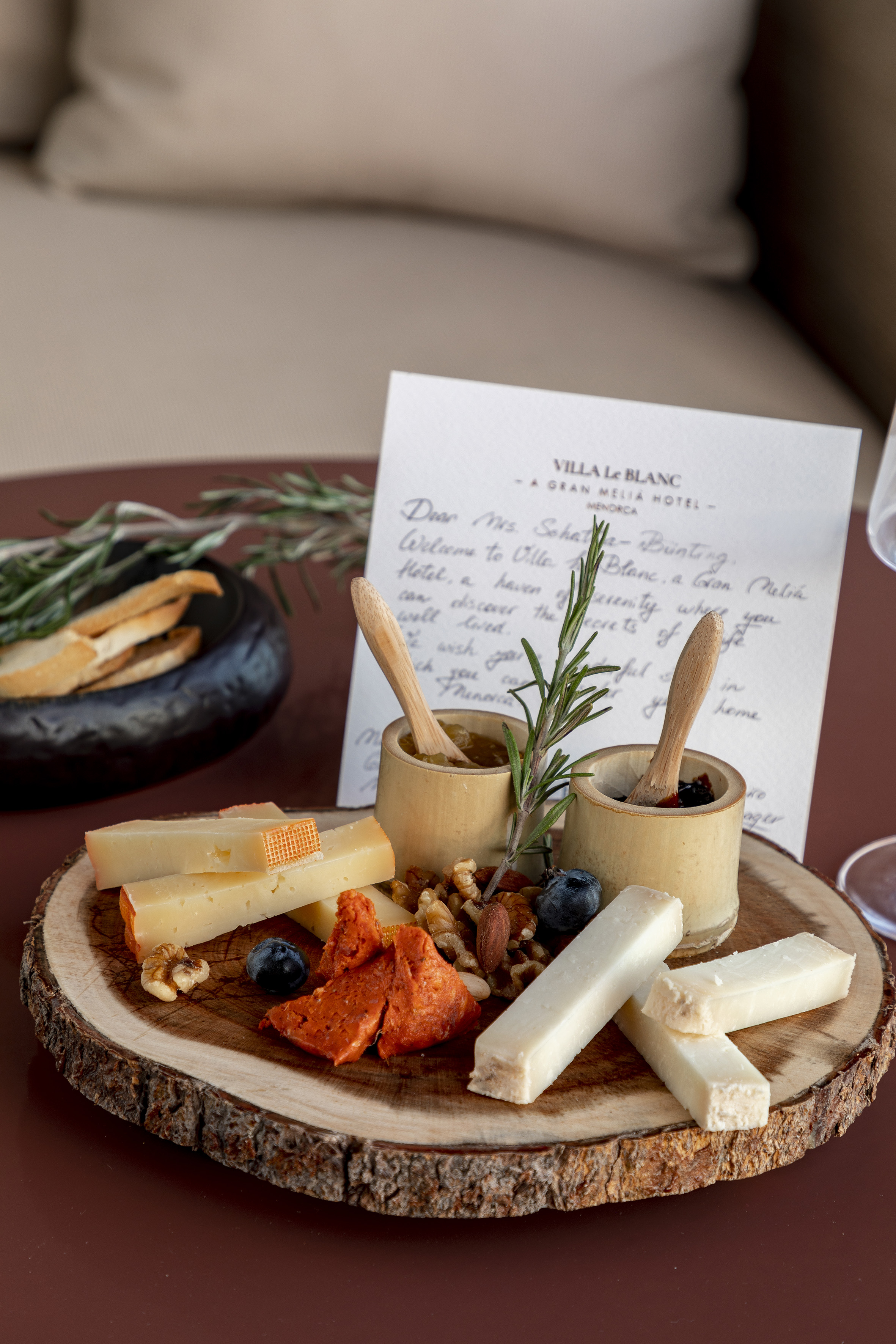 Menorca hotel welcome cheese board, nuts, fruit, preserves, and rosemary.
