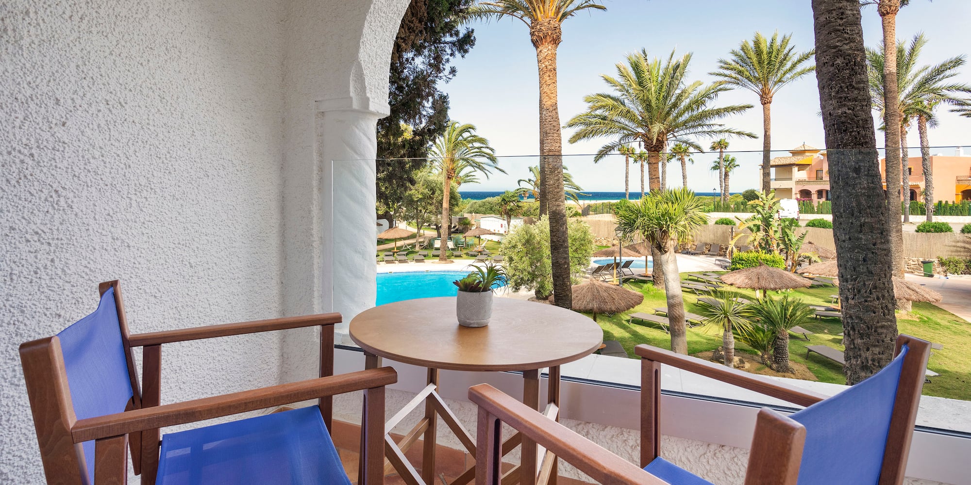 a patio with a table and chairs and a pool in the background