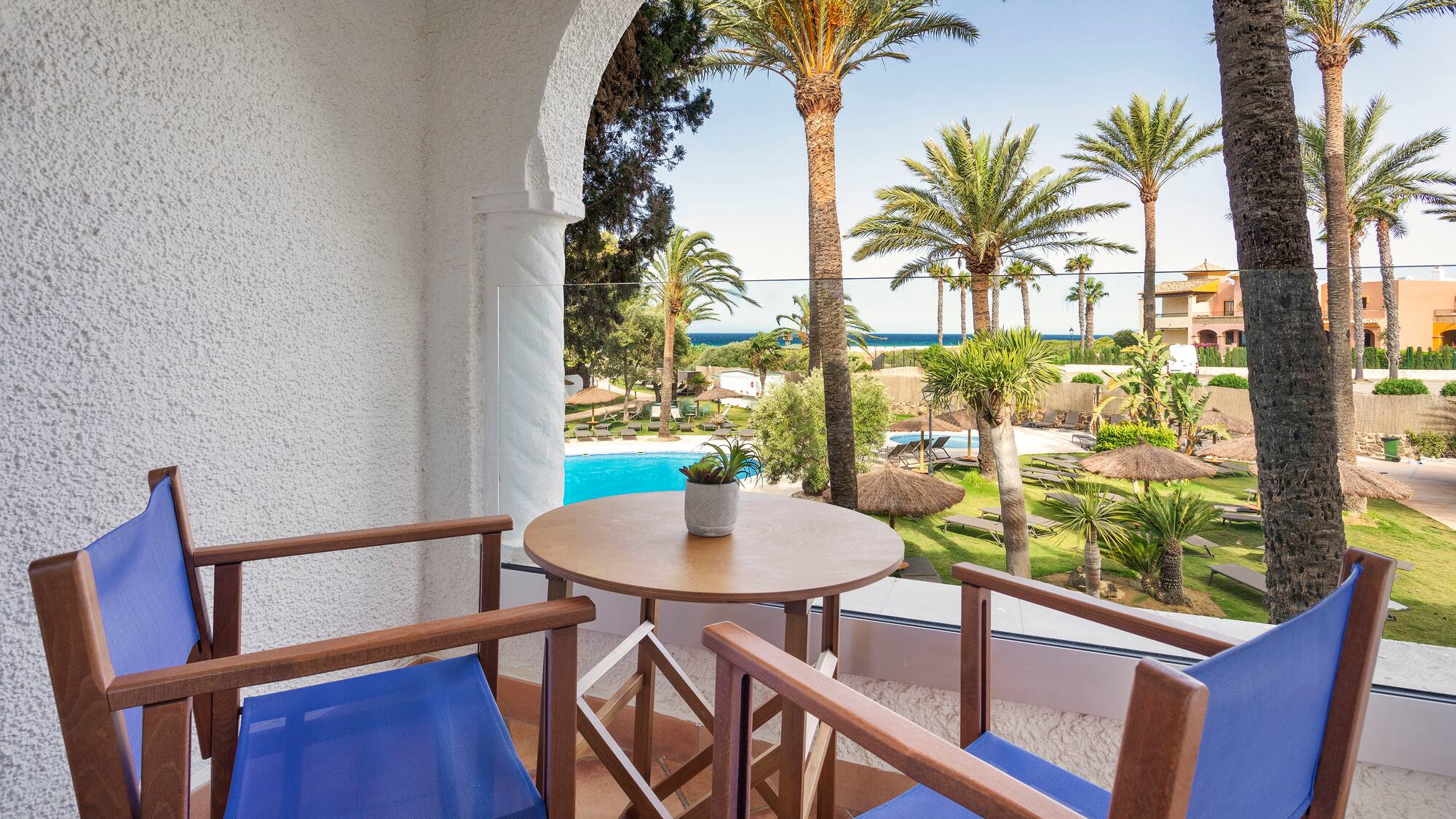 a patio with a table and chairs and a pool in the background