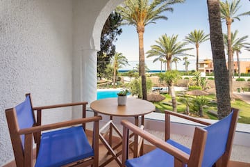 a patio with a table and chairs and a pool in the background