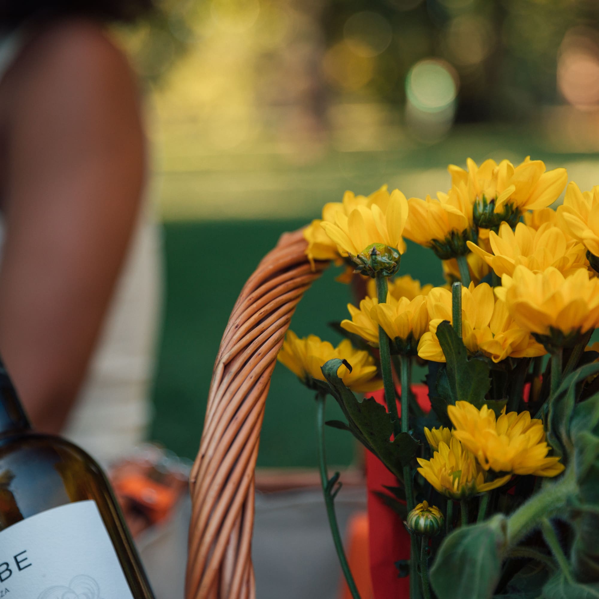 a basket of yellow flowers and a bottle of wine