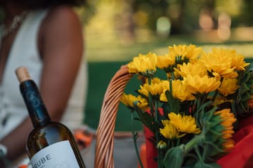 a basket of yellow flowers and a bottle of wine