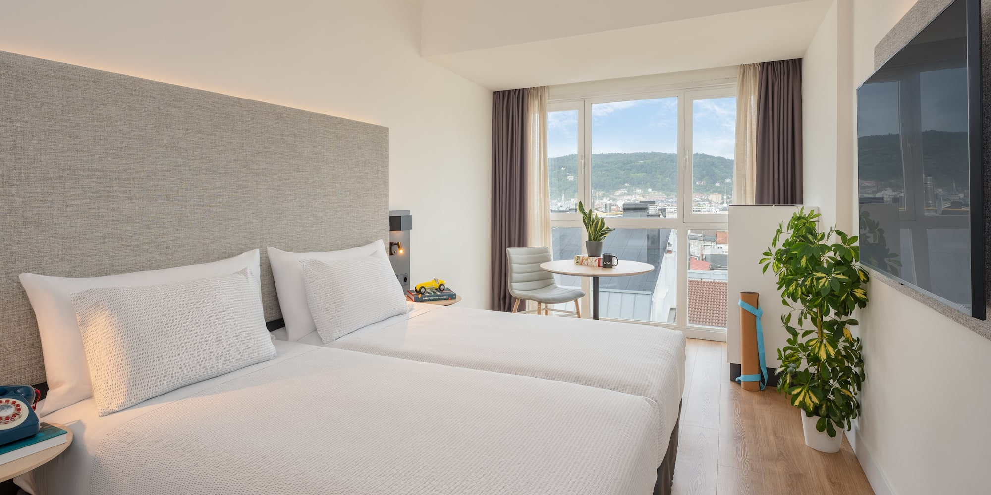 a room with two beds and a table and a plant