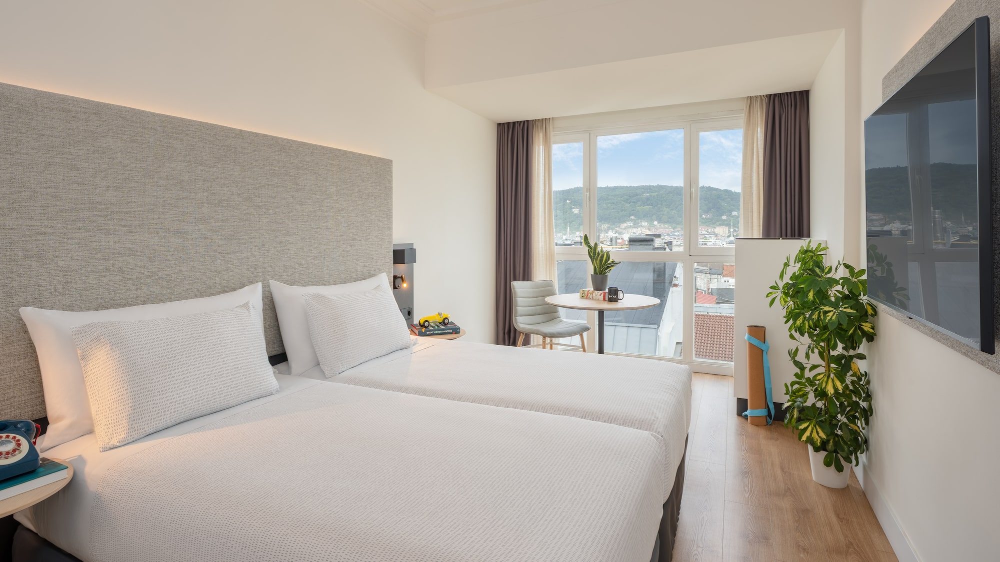 a room with two beds and a table and a plant