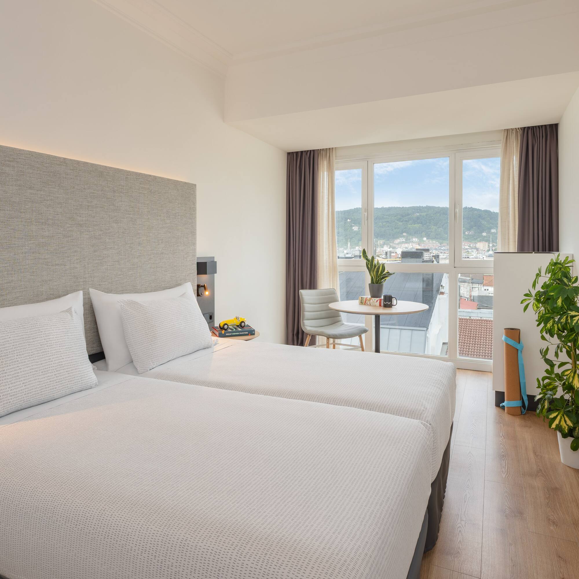 a room with two beds and a table and a plant