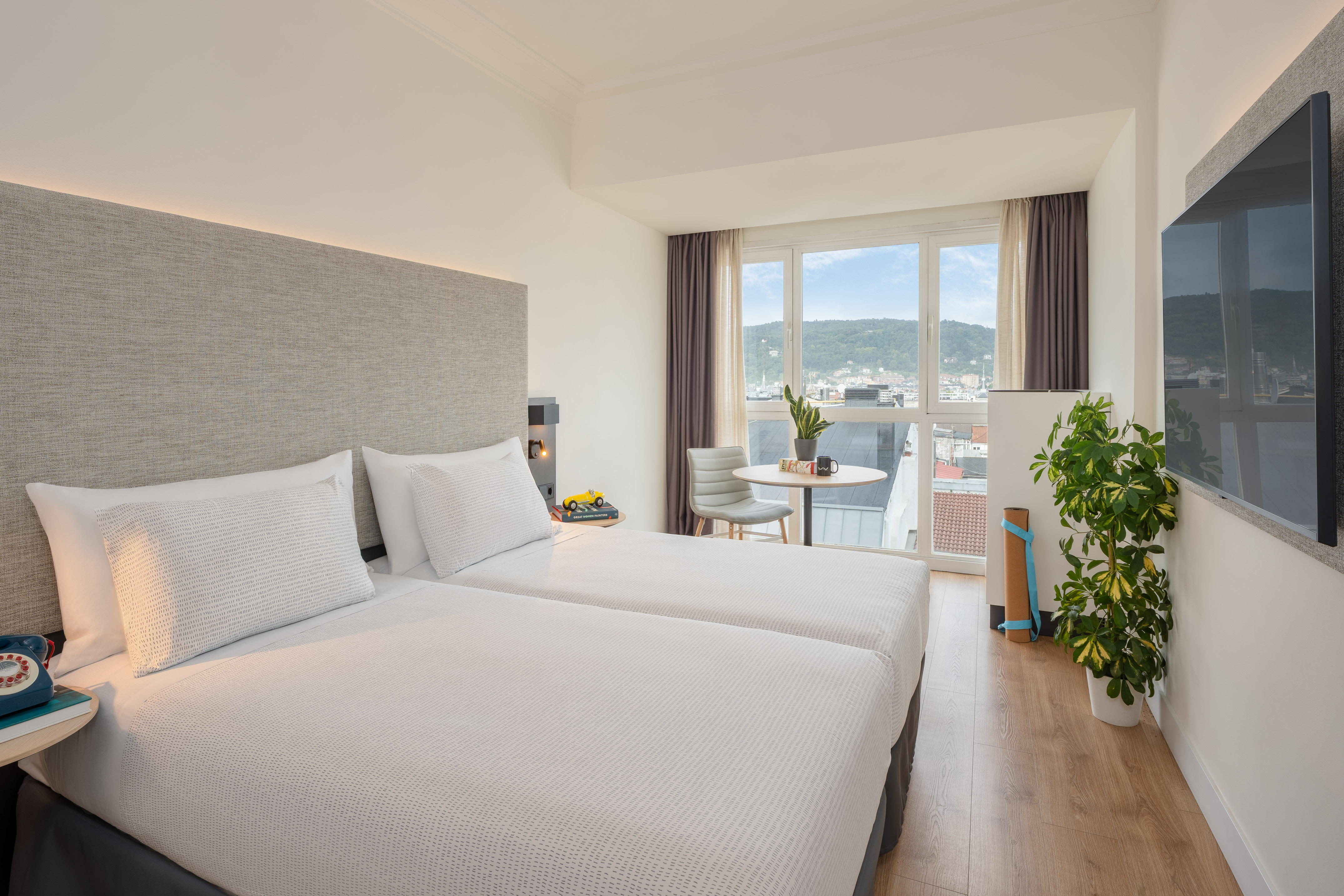 a room with two beds and a table and a plant