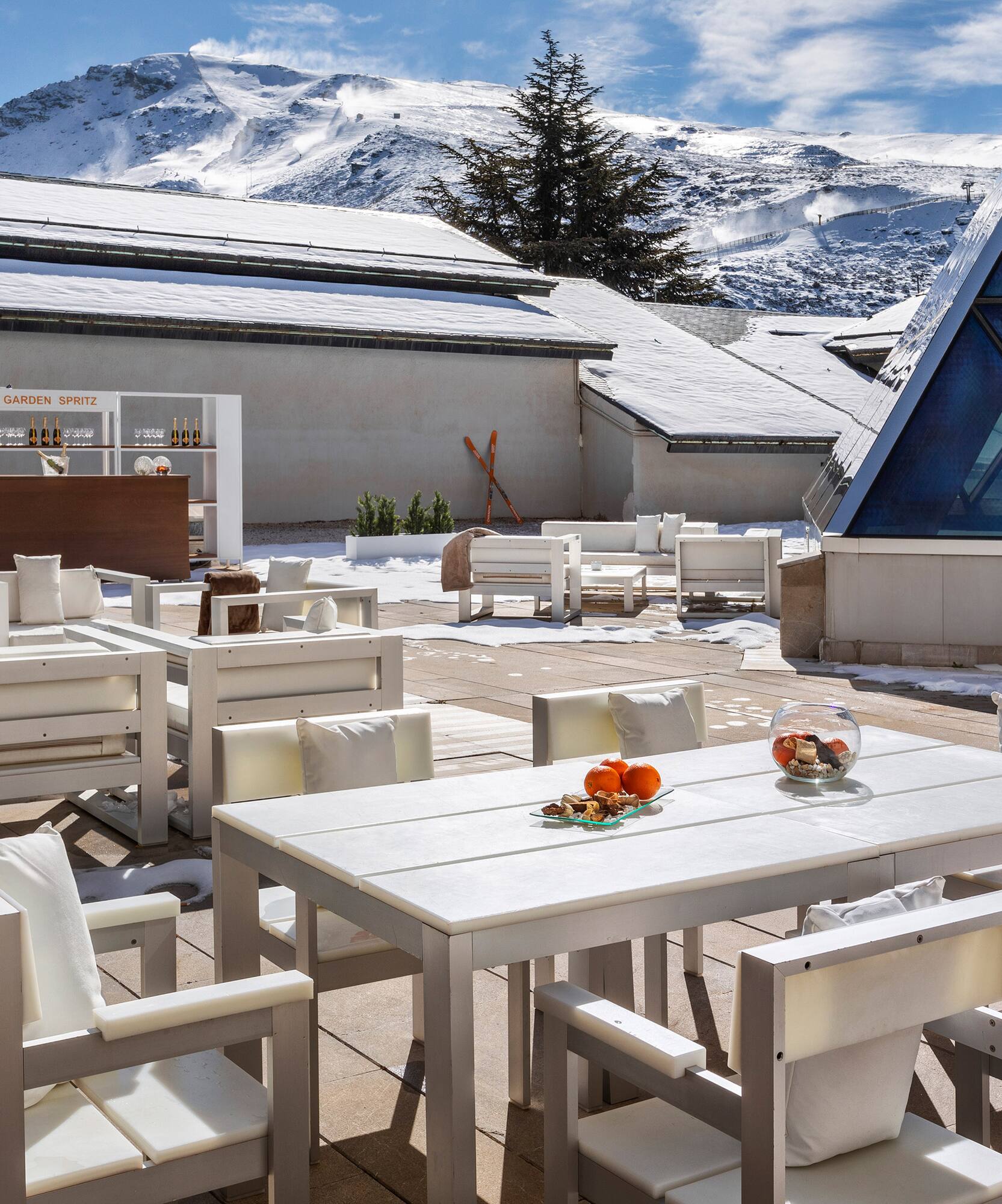 a white tables and chairs outside with snow covered mountains in the background