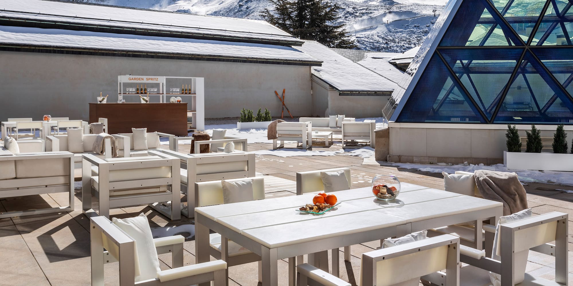 a white tables and chairs outside with snow covered mountains in the background