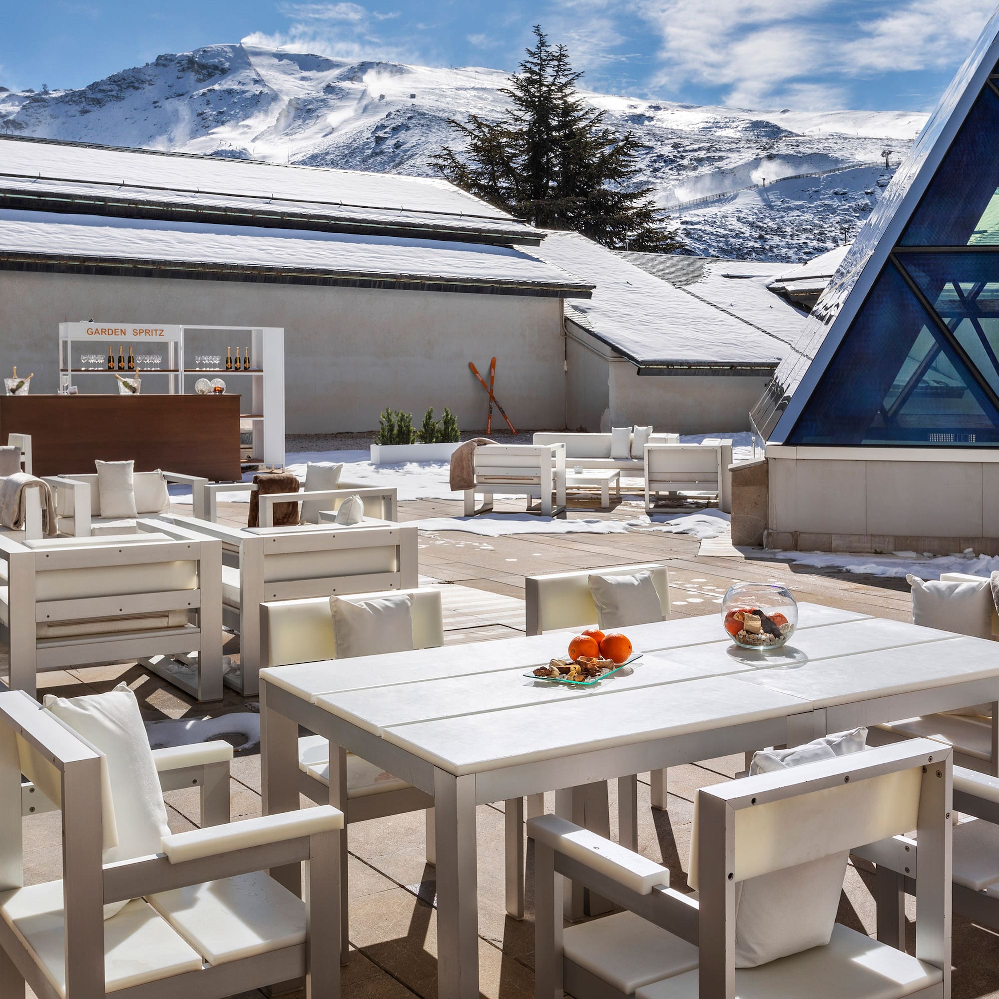 a white tables and chairs outside with snow covered mountains in the background