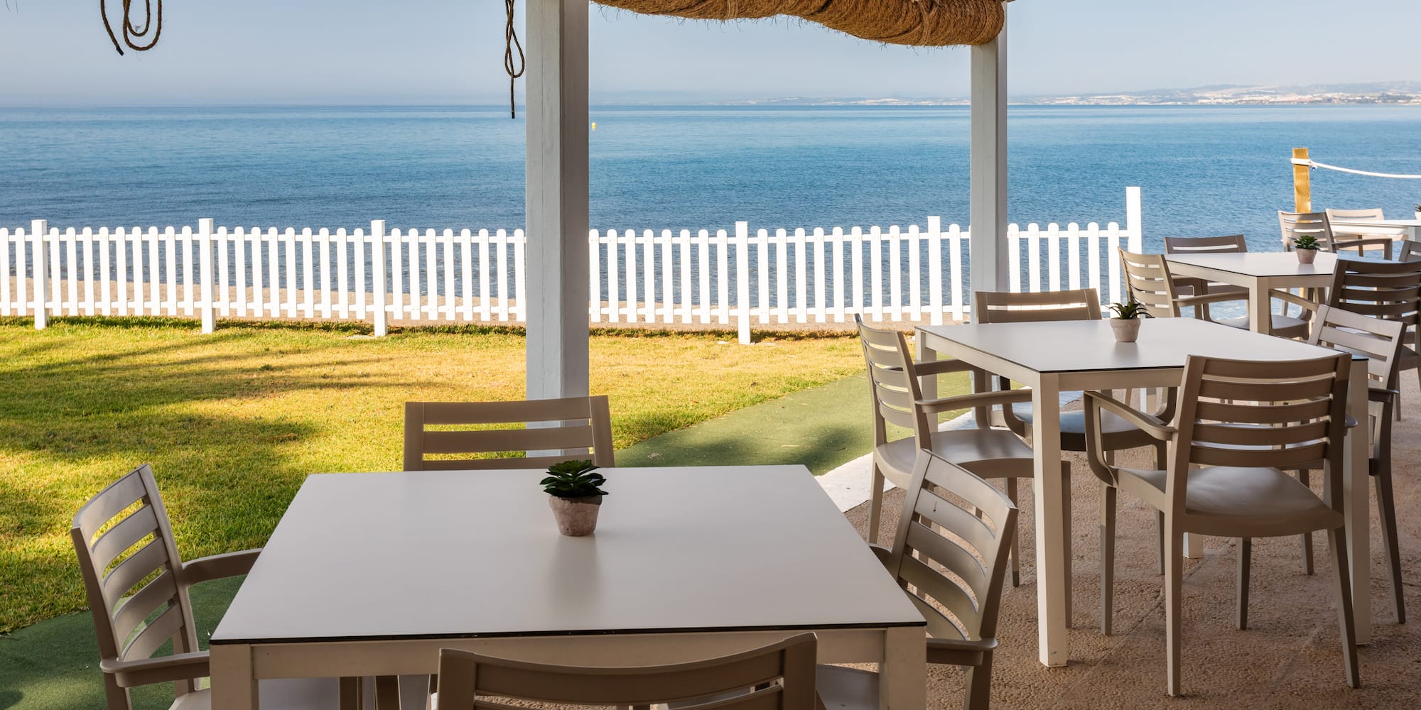 a table and chairs outside with a white fence and grass
