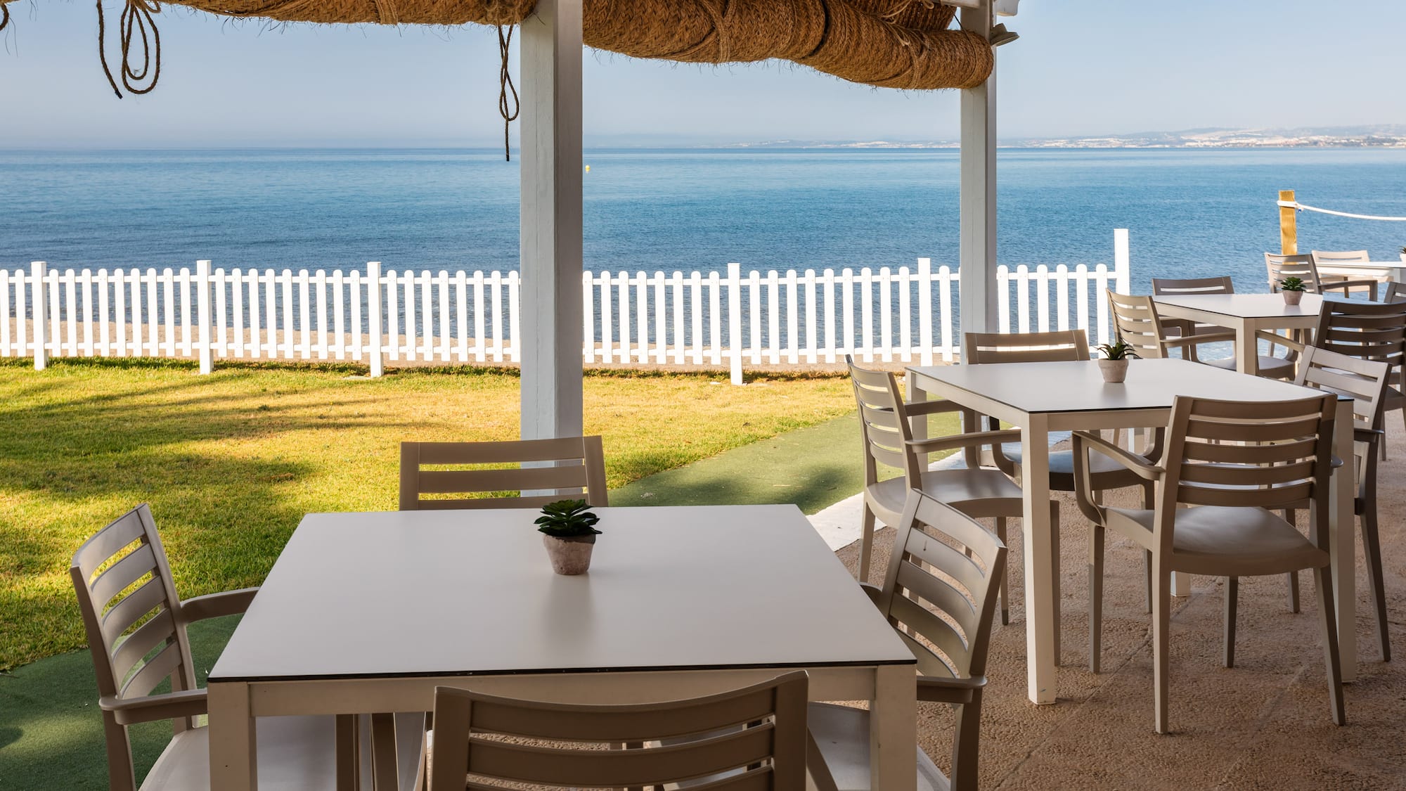 a table and chairs outside with a white fence and grass