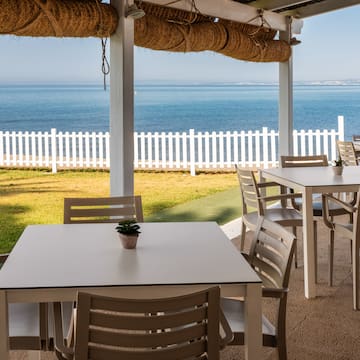 a table and chairs outside with a white fence and grass