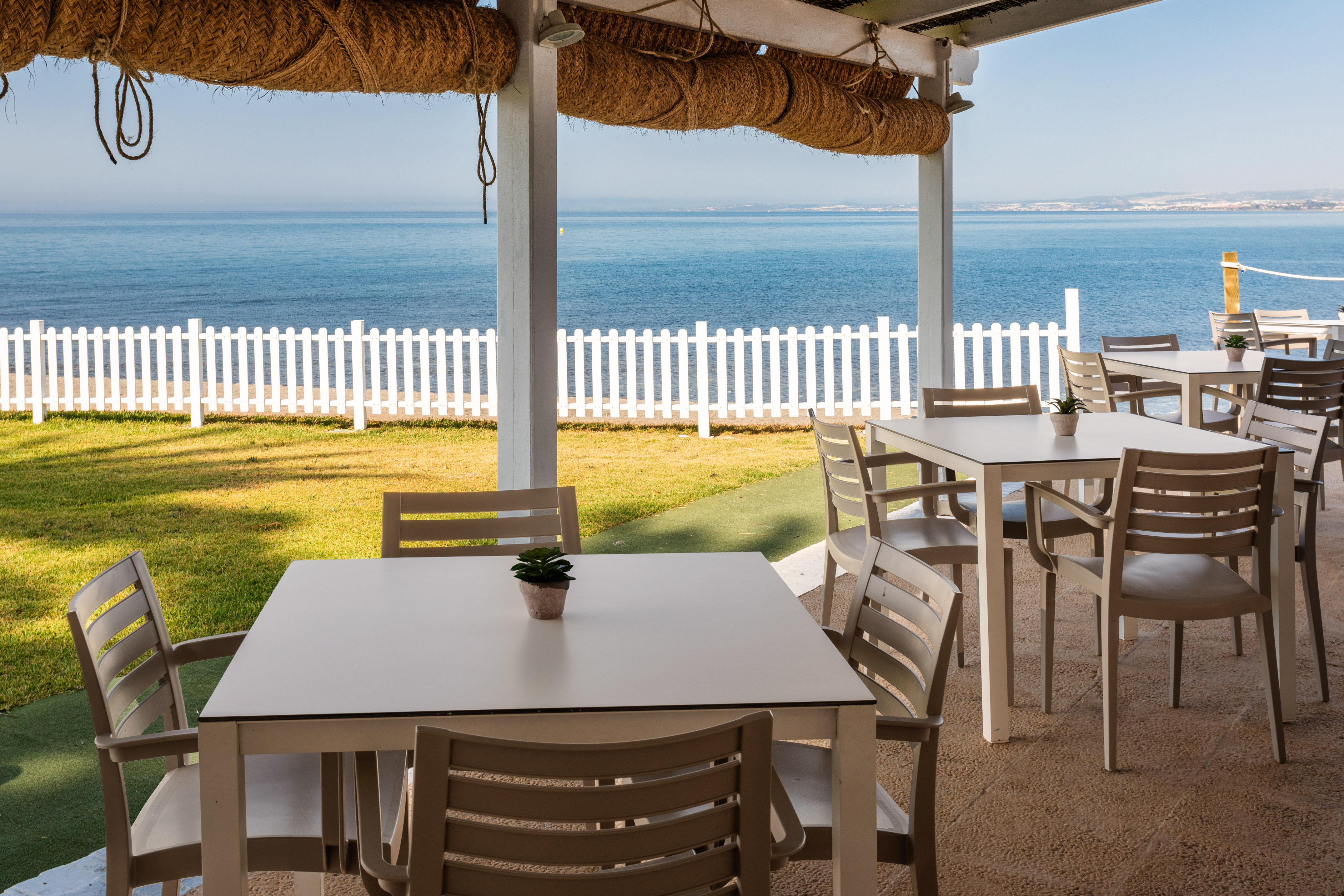 a table and chairs outside with a white fence and grass