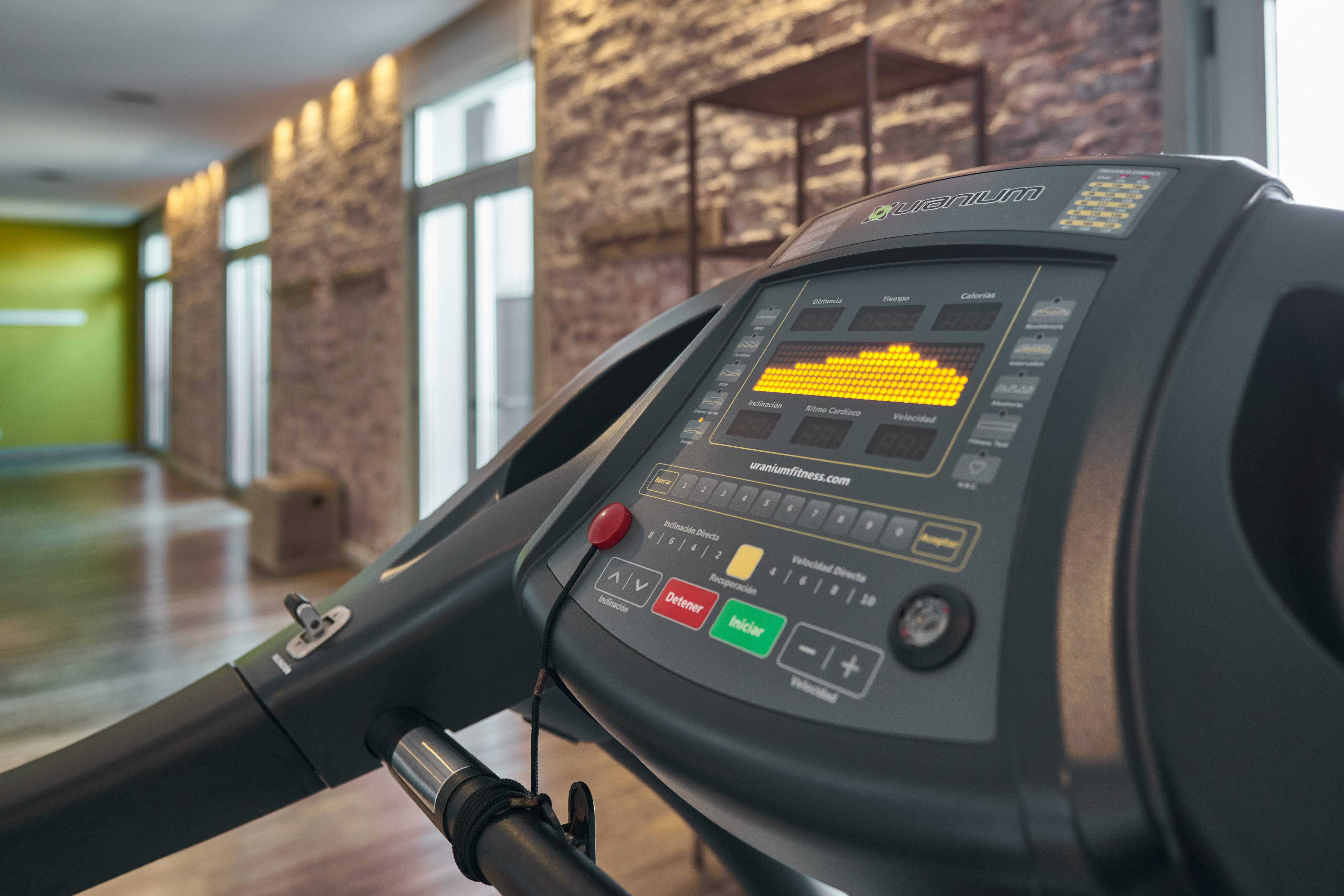 Uranium Fitness treadmill control panel with illuminated digital display in a gym.