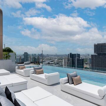 a rooftop pool with white couches and a city view