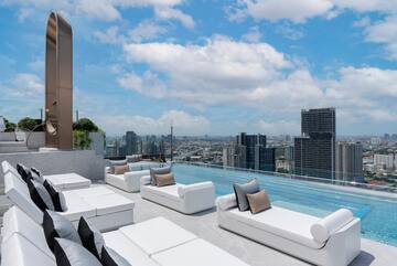 a rooftop pool with white couches and a city view