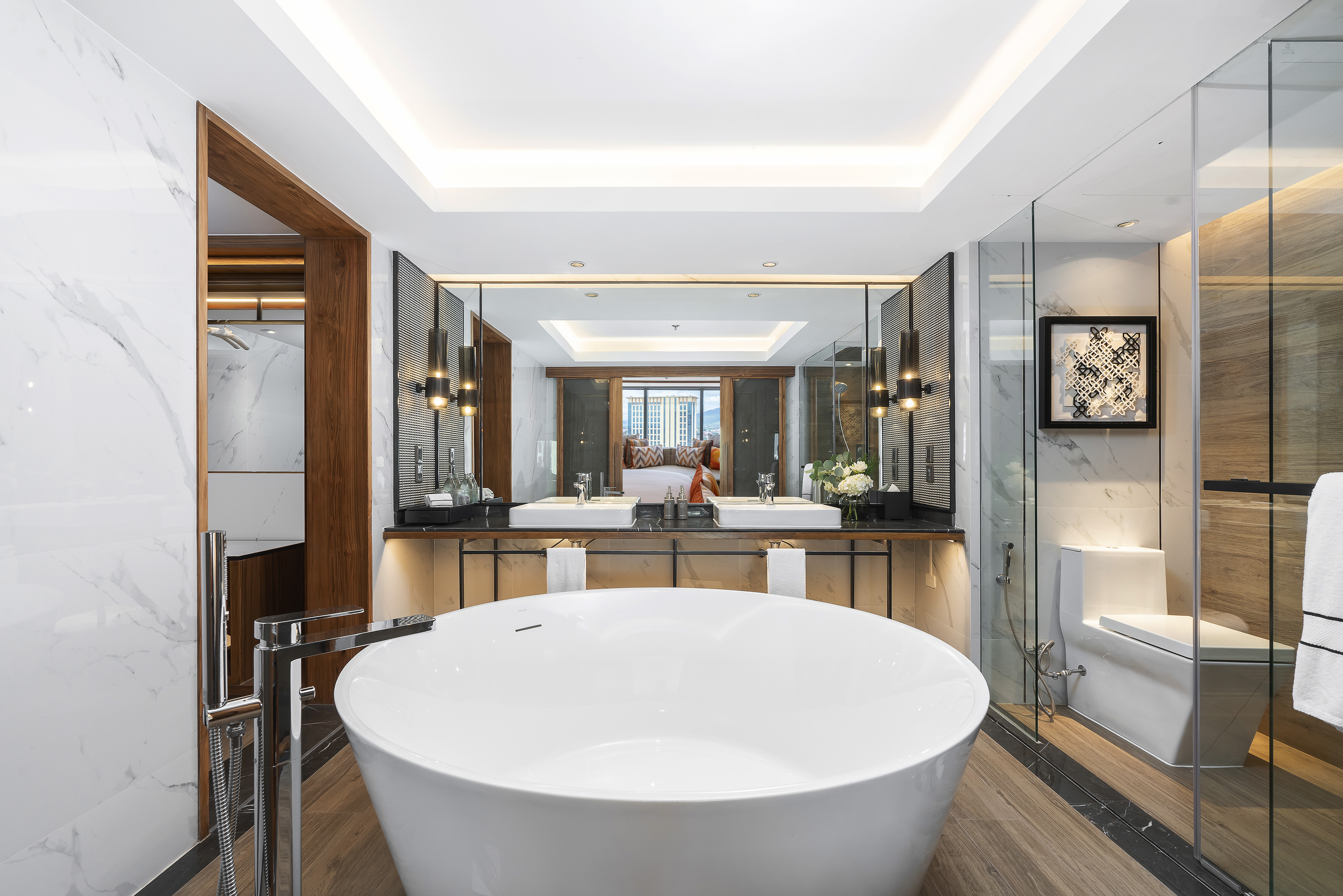 Modern luxury hotel bathroom with freestanding tub, double vanity, and wood floor.