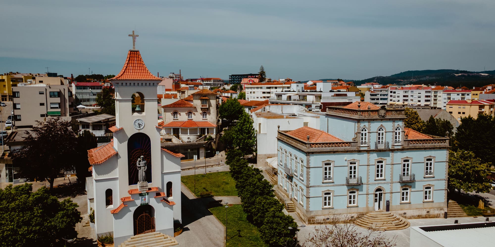 a white building with a bell tower and a green lawn