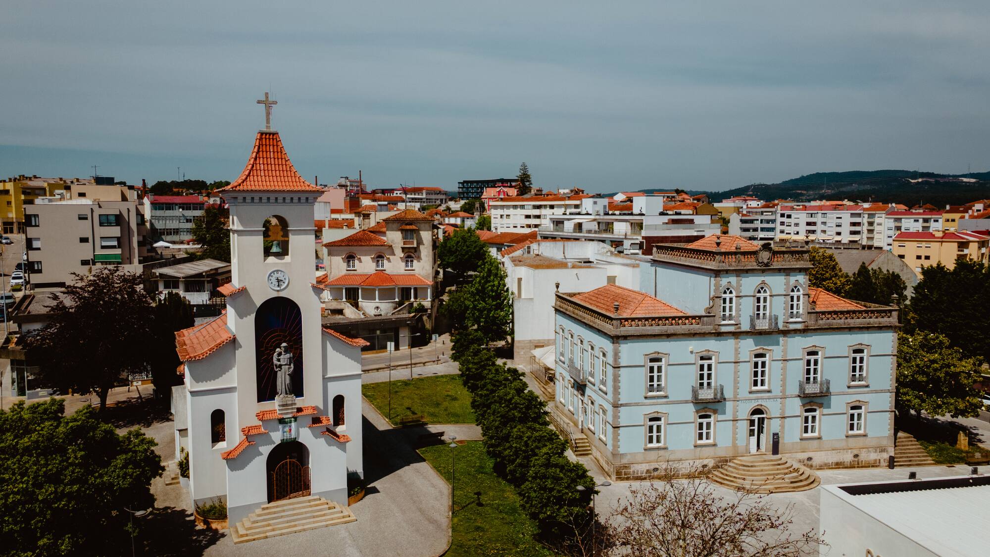a white building with a bell tower and a green lawn