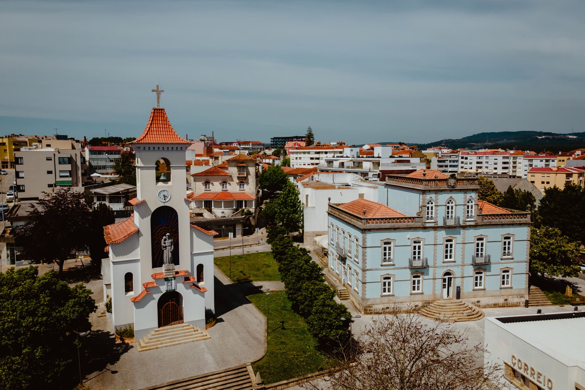 a white building with a bell tower and a green lawn