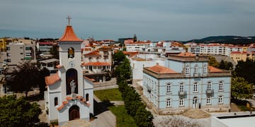 a white building with a bell tower and a green lawn