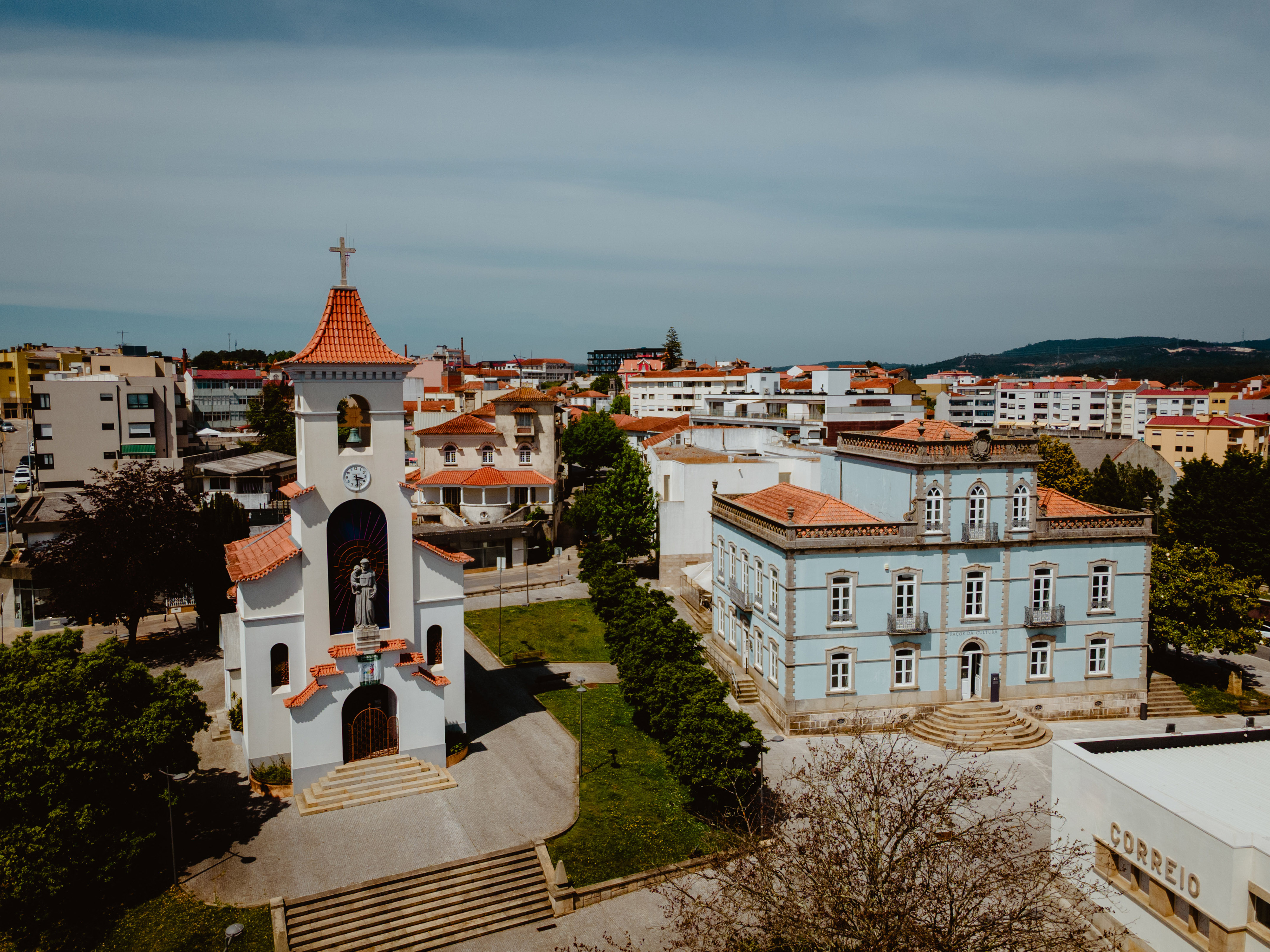 a white building with a bell tower and a green lawn