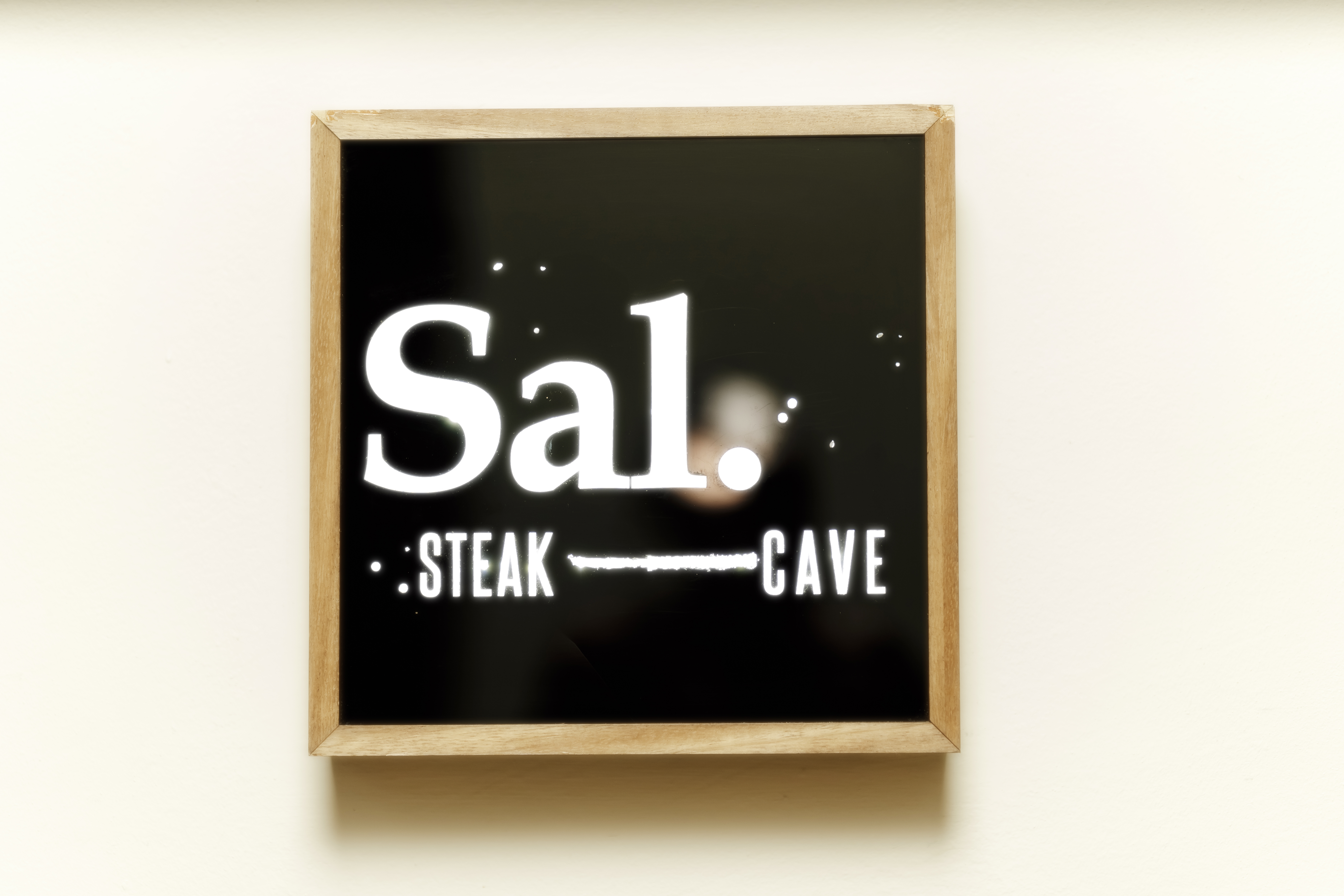 Illuminated Sal. STEAK CAVE sign with a wooden frame.