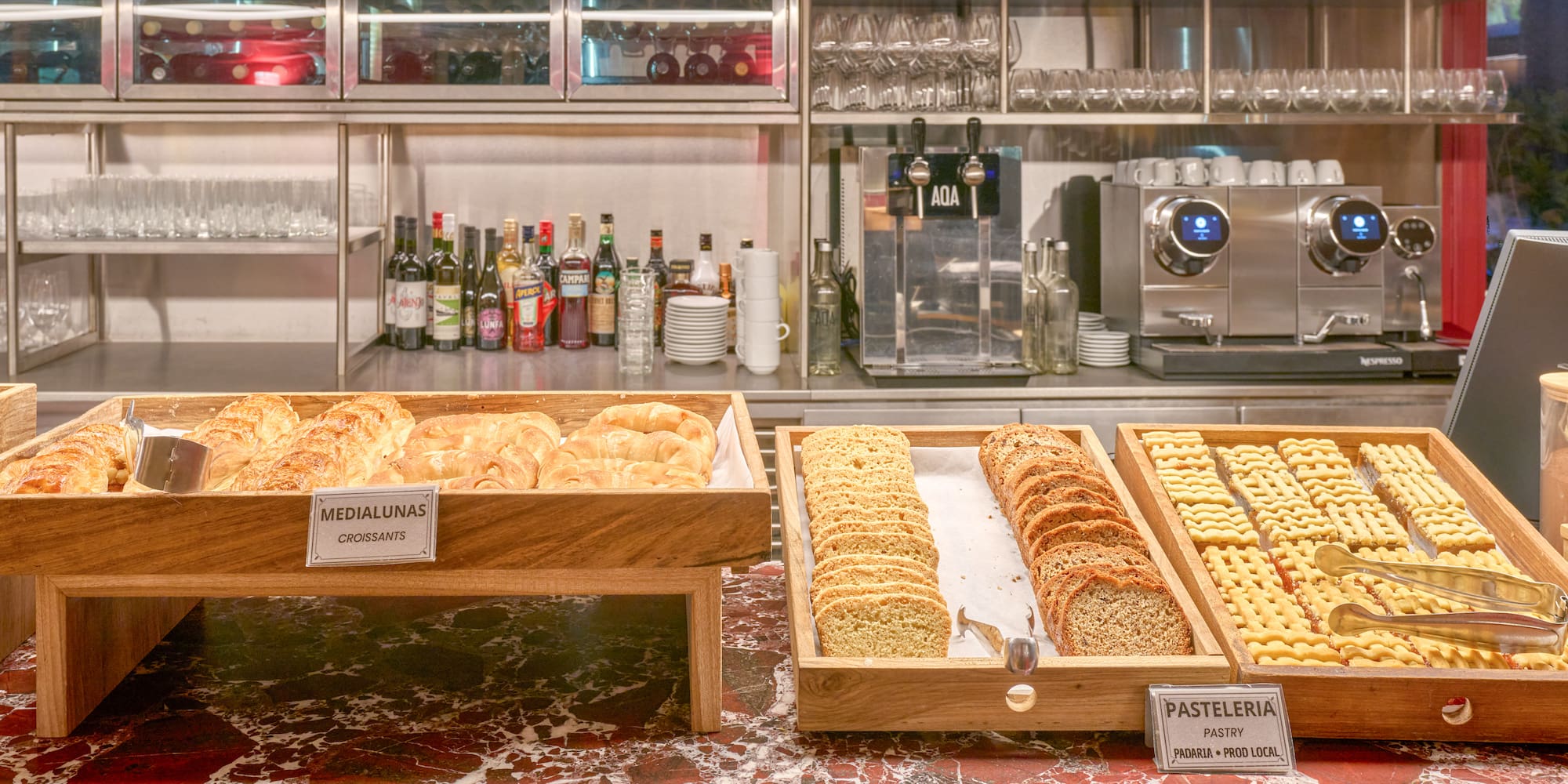 Breakfast buffet with croissants, pastries, bread, and modern coffee station.
