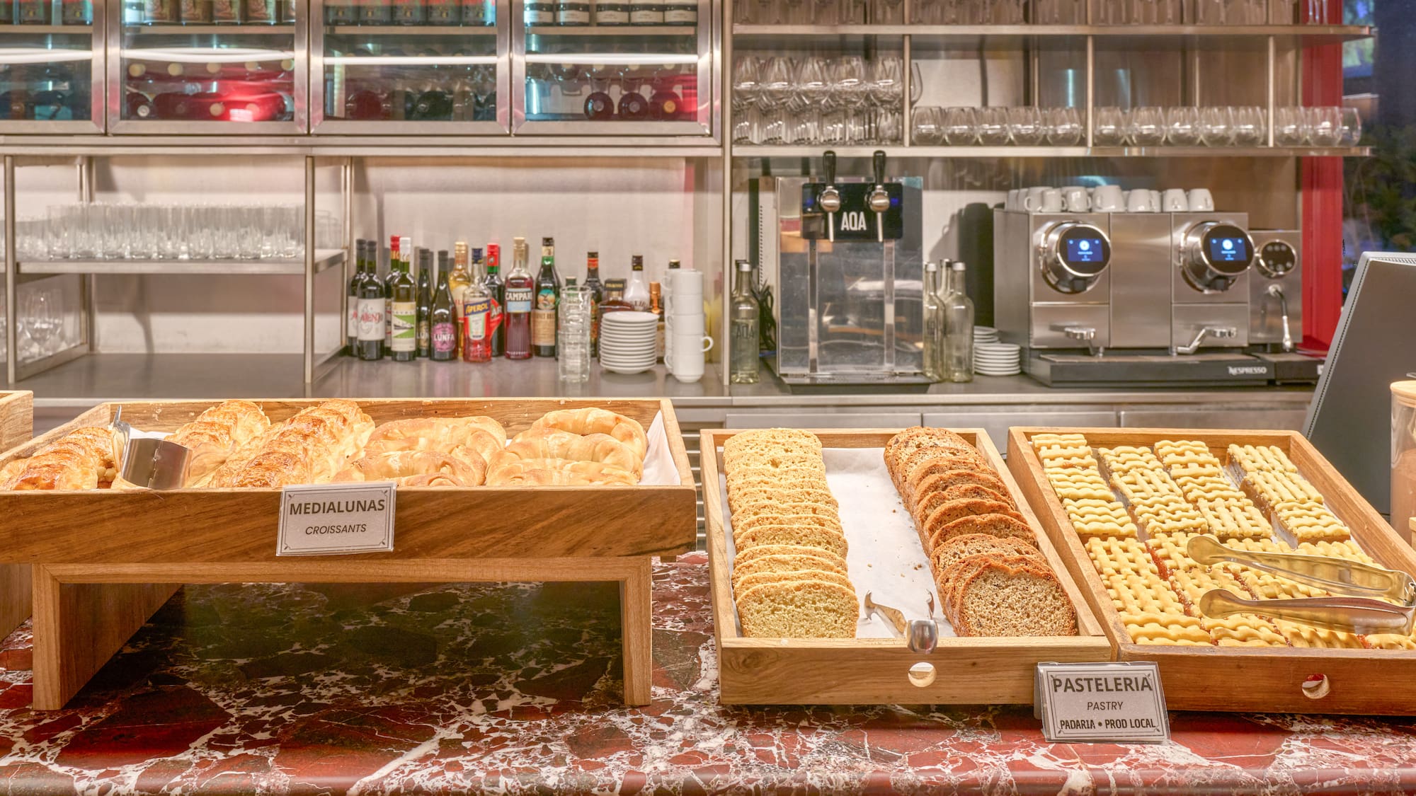 Breakfast buffet with croissants, pastries, bread, and modern coffee station.