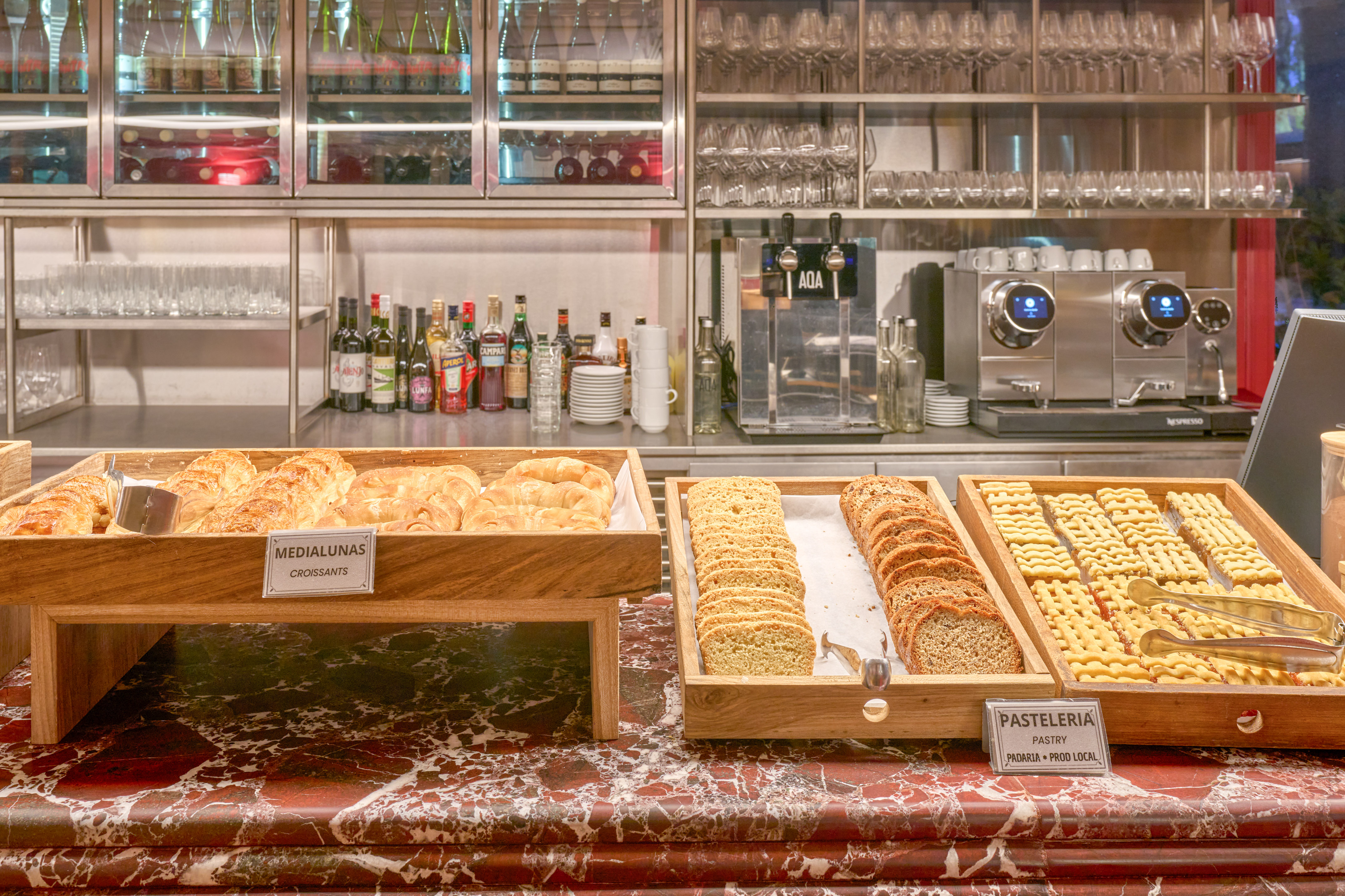 Breakfast buffet with croissants, pastries, bread, and modern coffee station.