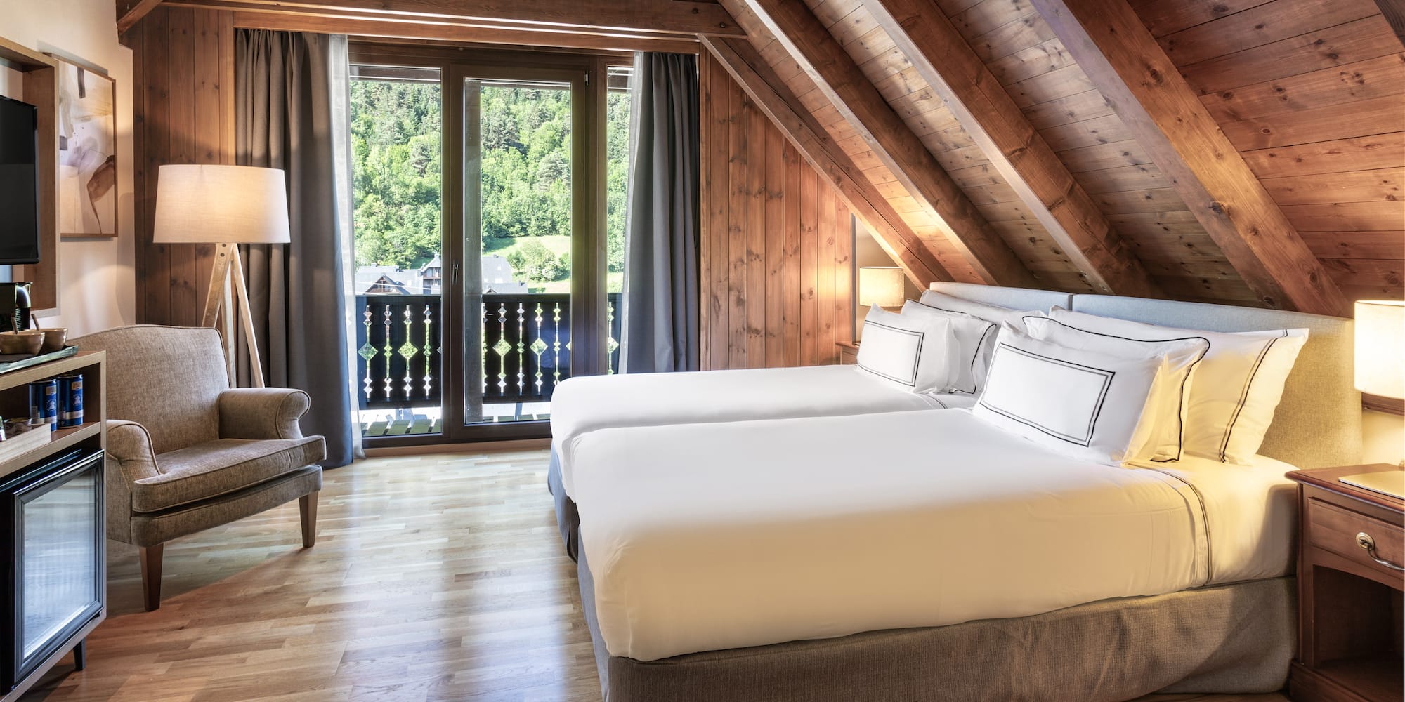 Habitación de hotel ático, camas individuales, madera y balcón con vistas.