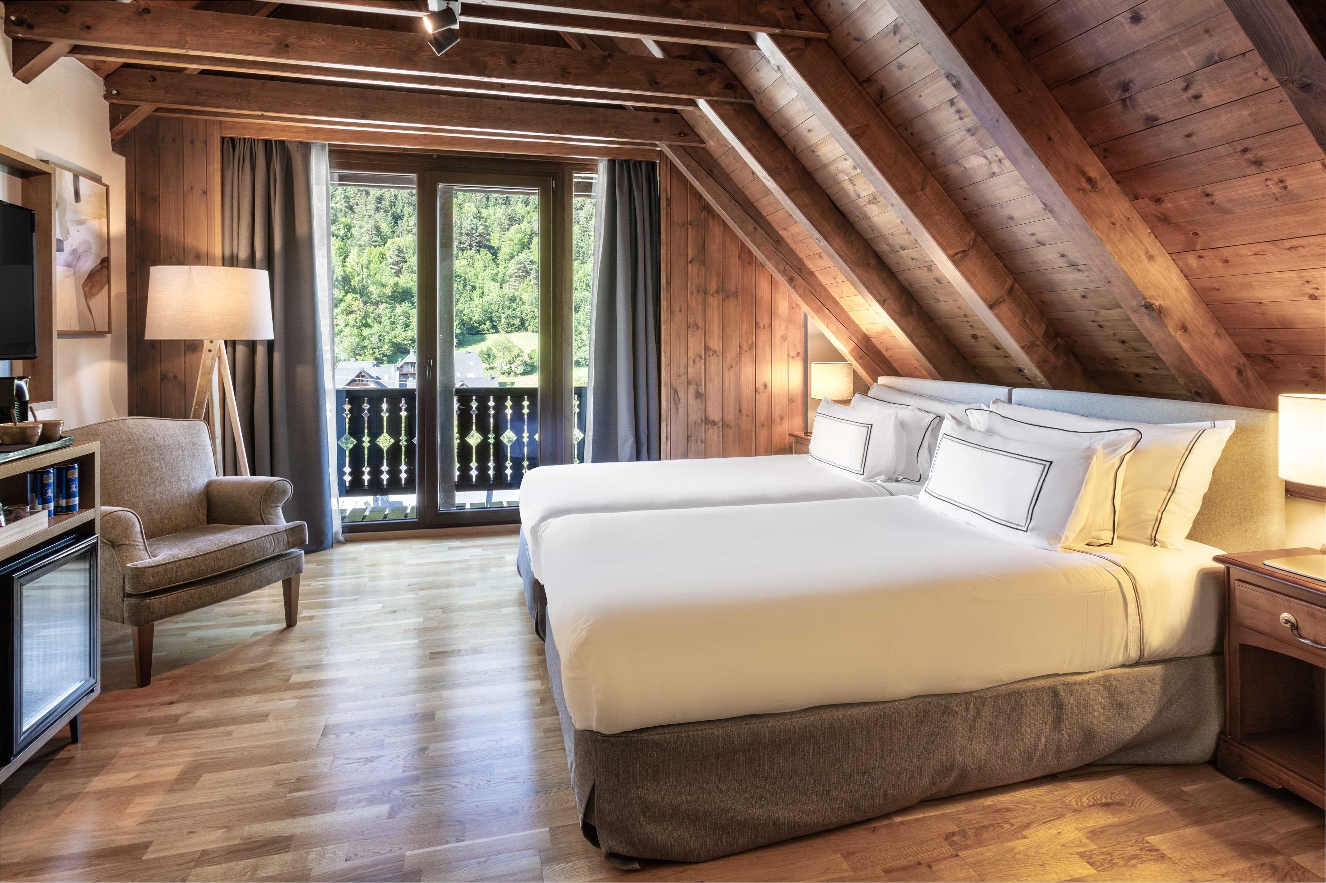 Habitación de hotel ático, camas individuales, madera y balcón con vistas.
