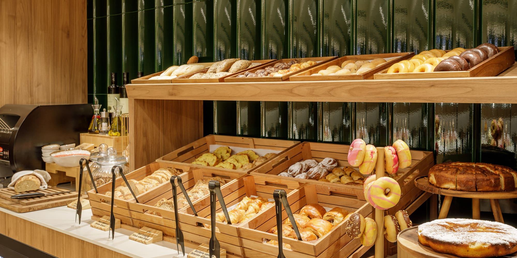 Breakfast buffet with fresh pastries, breads, and colorful donuts on display.