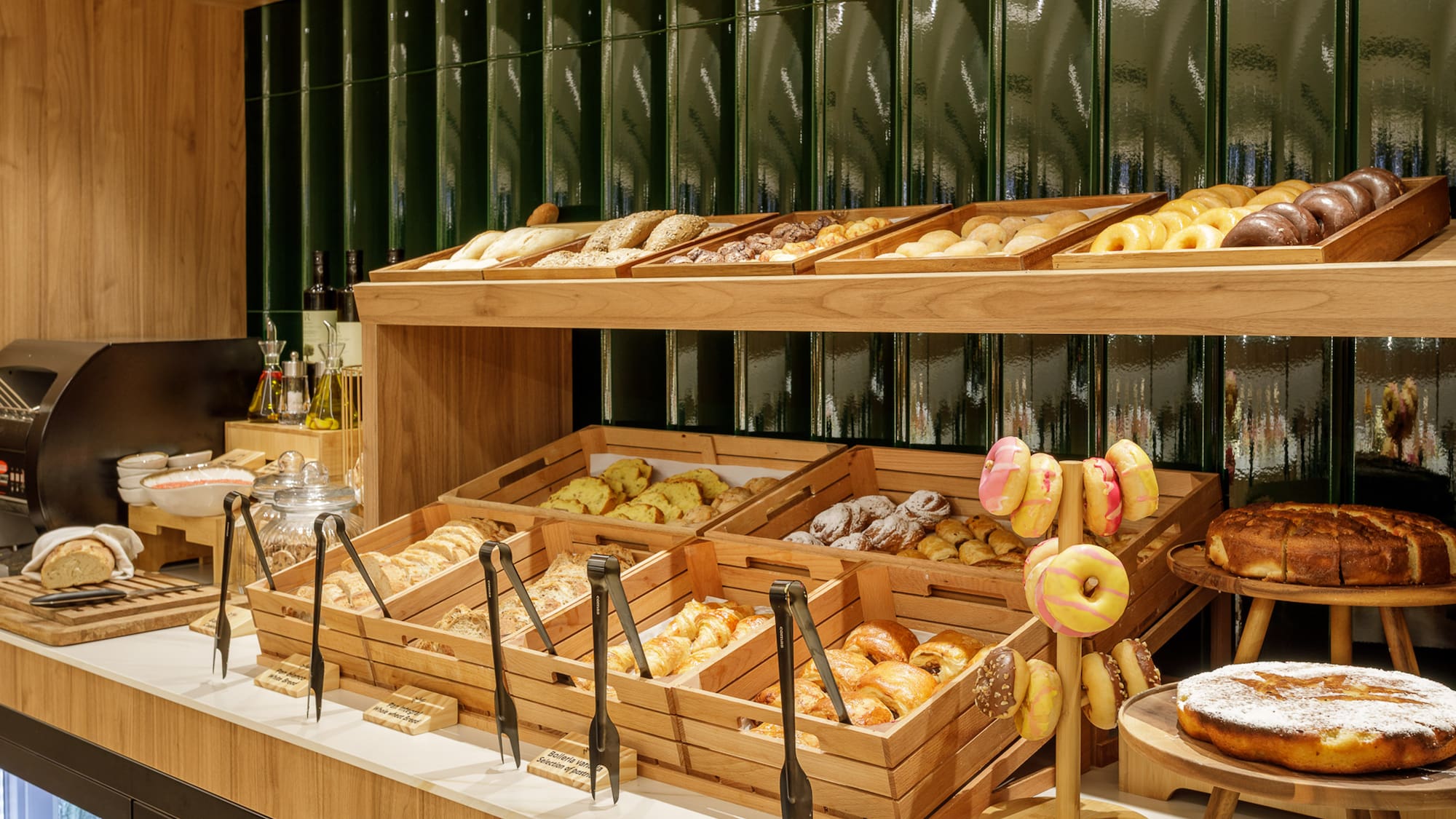 Breakfast buffet with fresh pastries, breads, and colorful donuts on display.