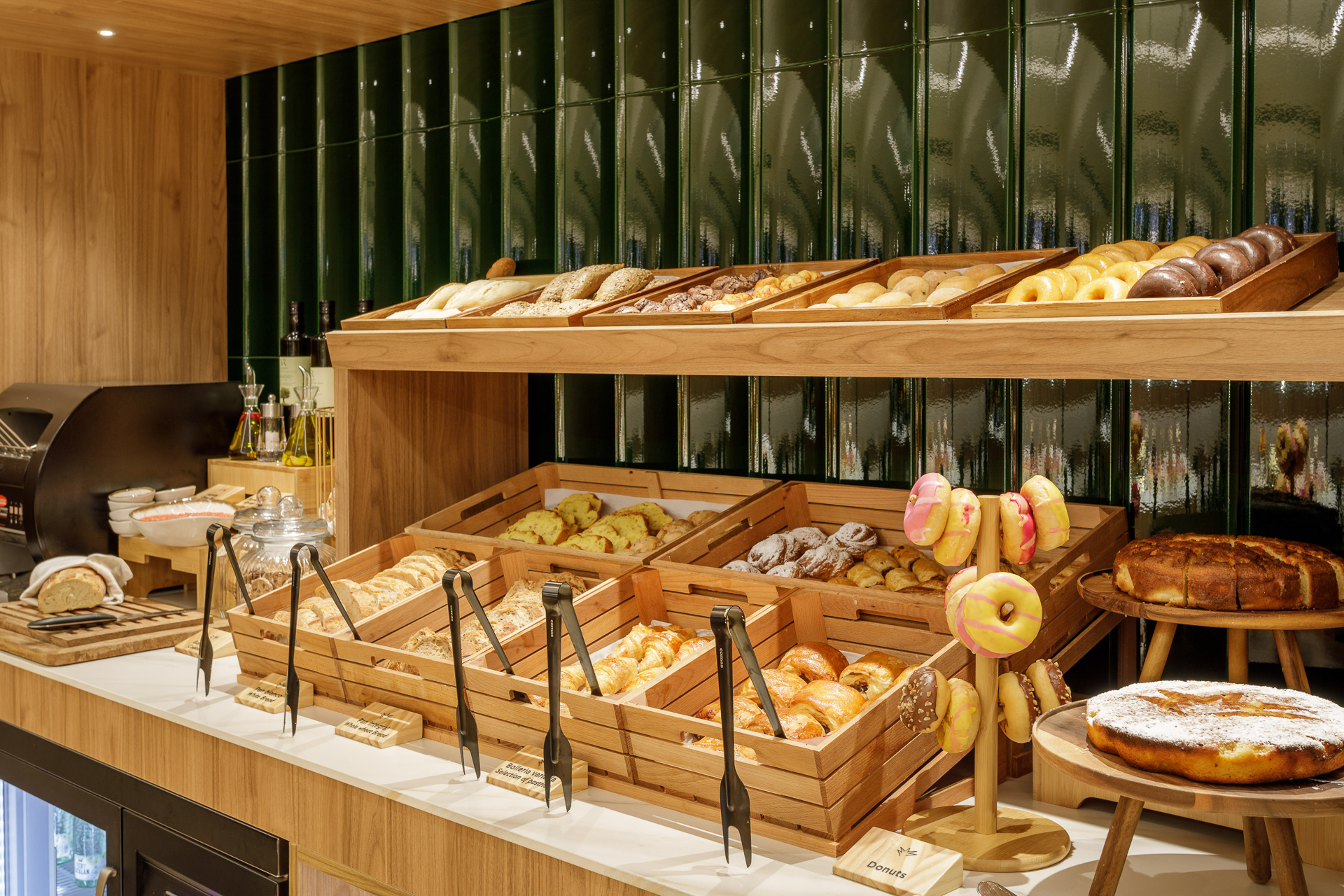 Breakfast buffet with fresh pastries, breads, and colorful donuts on display.