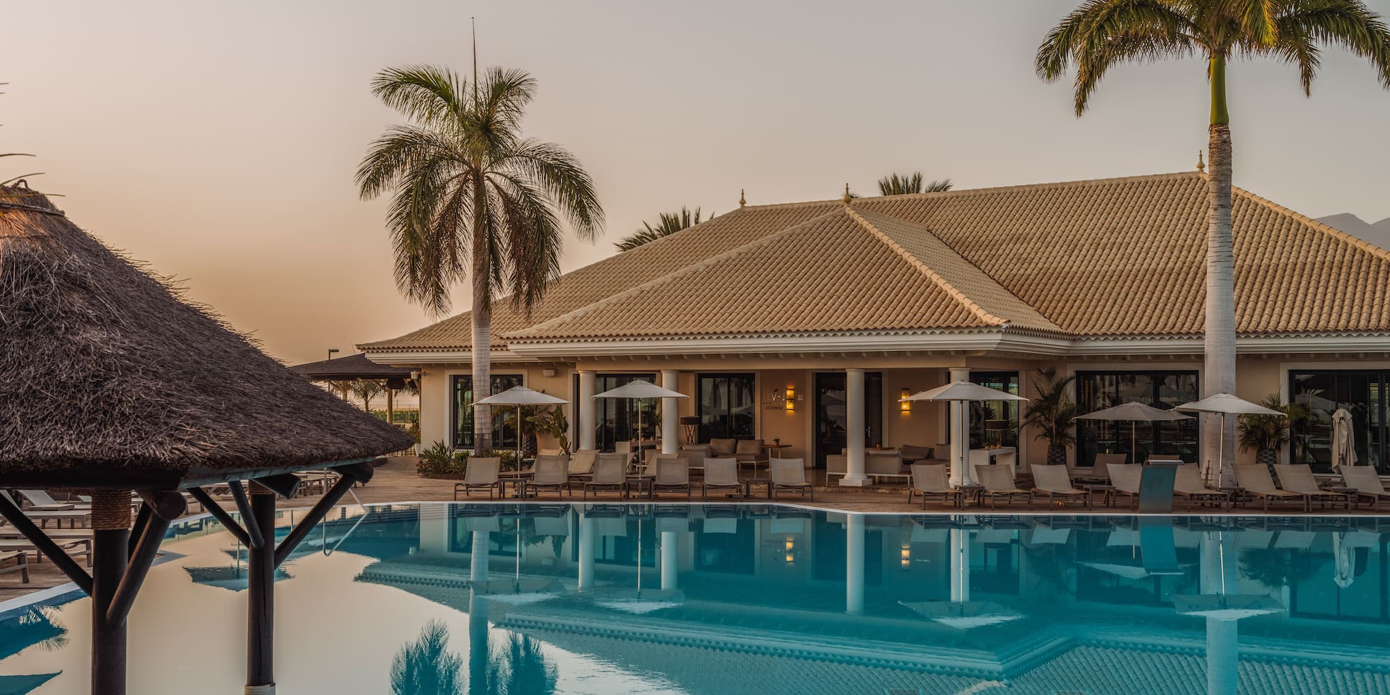 a pool with palm trees and a building