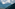 Forested mountain slope under cloudy sky overlooking a vast, hazy valley.