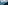 Forested mountain slope under cloudy sky overlooking a vast, hazy valley.