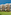 Sunny hotel building with balconies and a lush green lawn.
