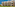 Sunny resort building with multiple balconies, green lawn, and garden landscaping.