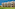 Sunny resort building with multiple balconies, green lawn, and garden landscaping.