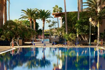 a pool with palm trees and a building