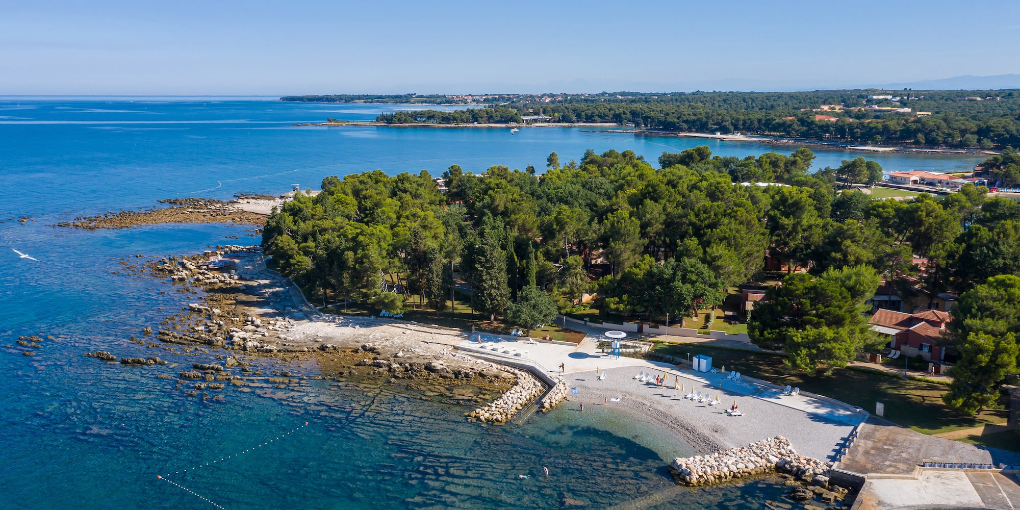 a beach with trees and rocks in the water