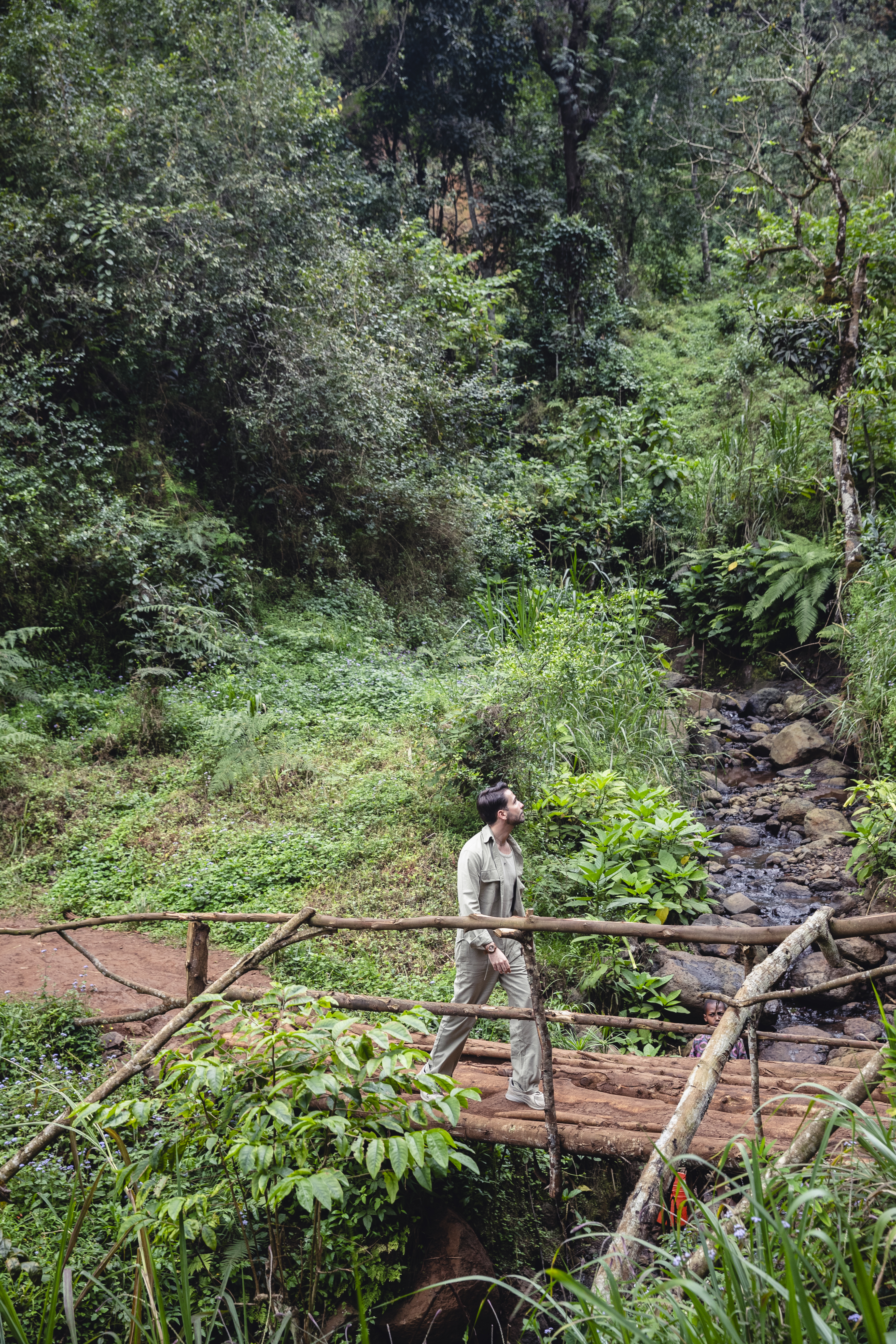a man walking on a bridge in a forest