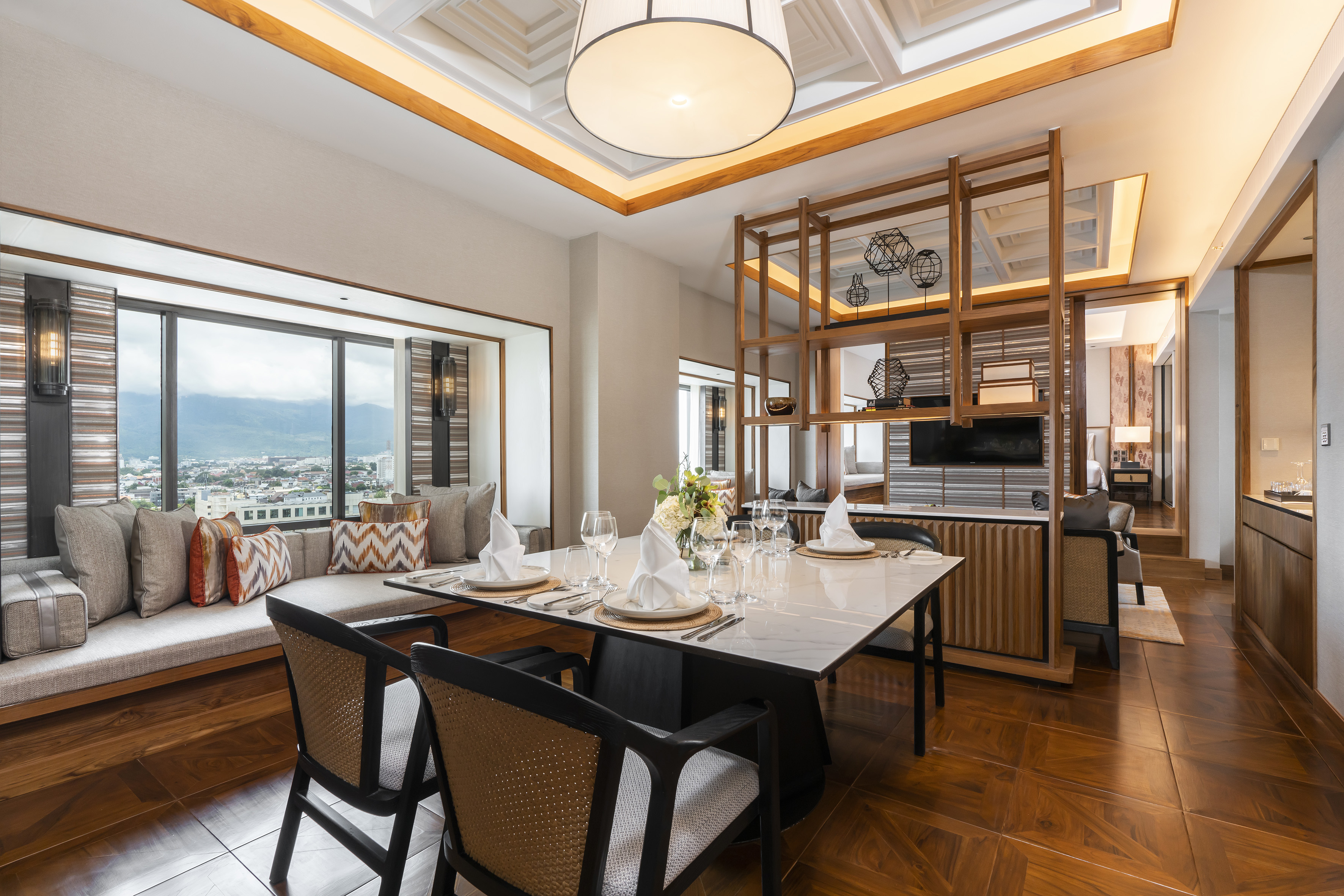 Spacious dining area in a modern suite with city view, marble table, and wood details.
