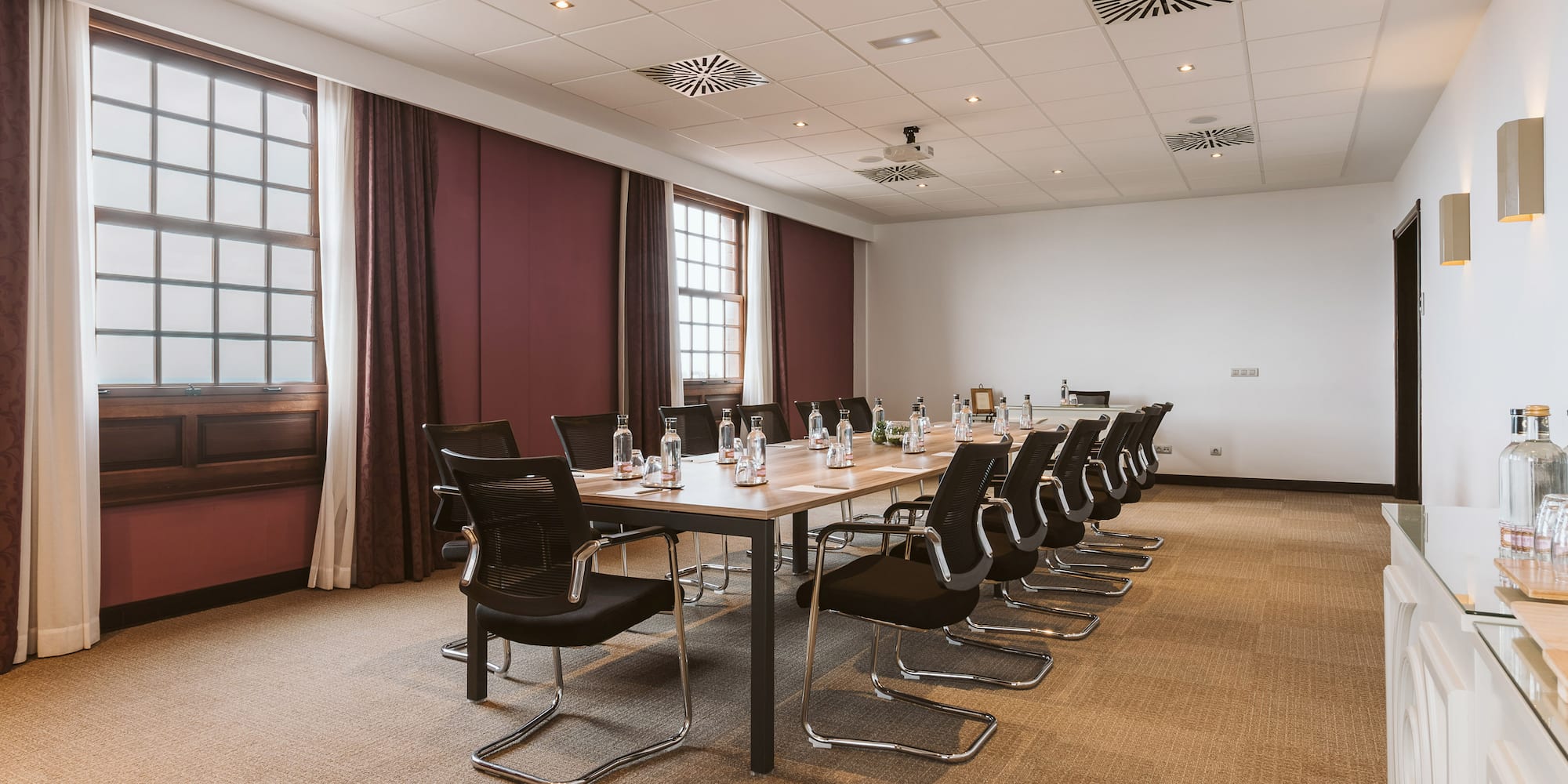Professional meeting room with boardroom table, ergonomic chairs, and windows.