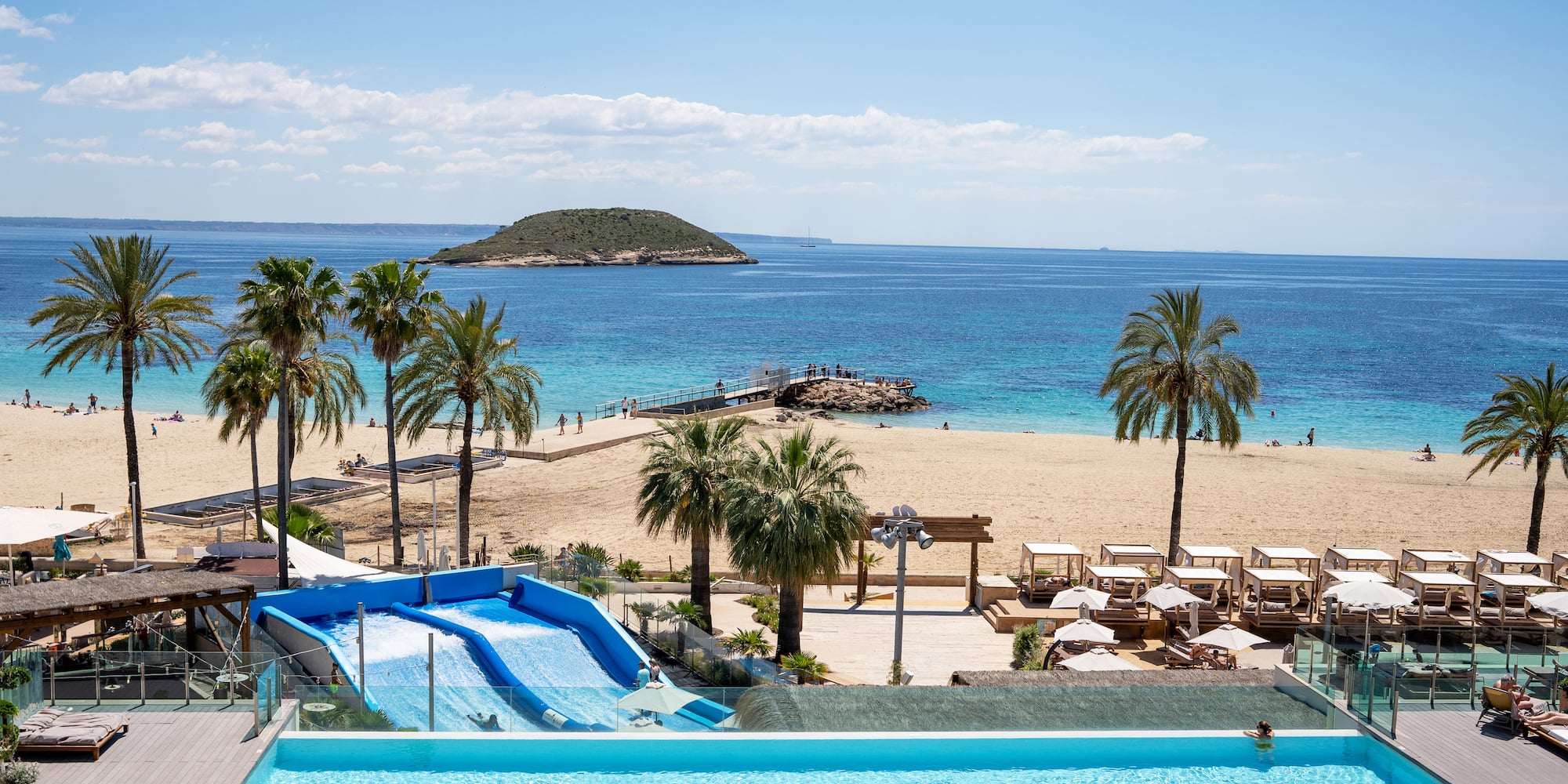 a pool with water slides and palm trees on a beach