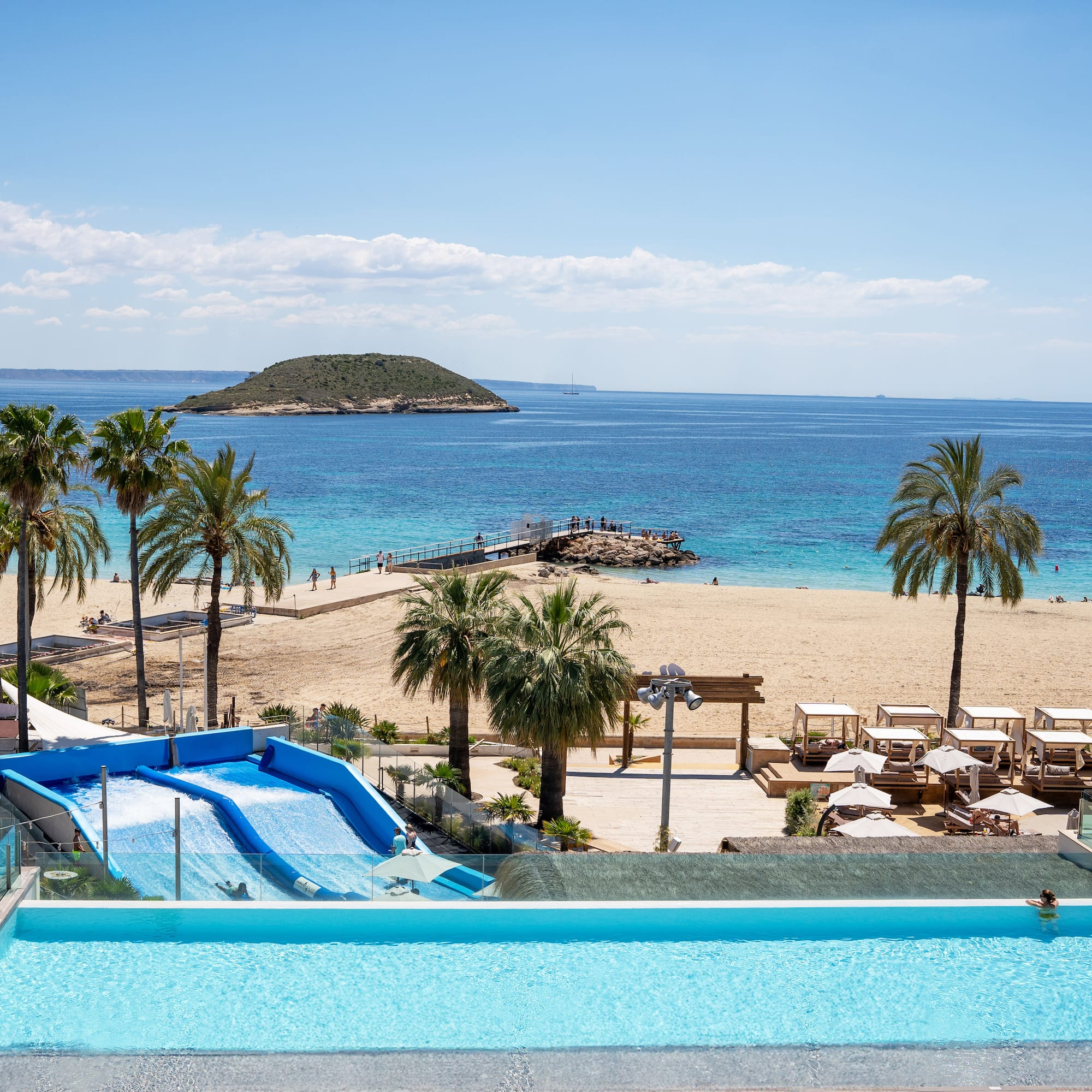 a pool with water slides and palm trees on a beach