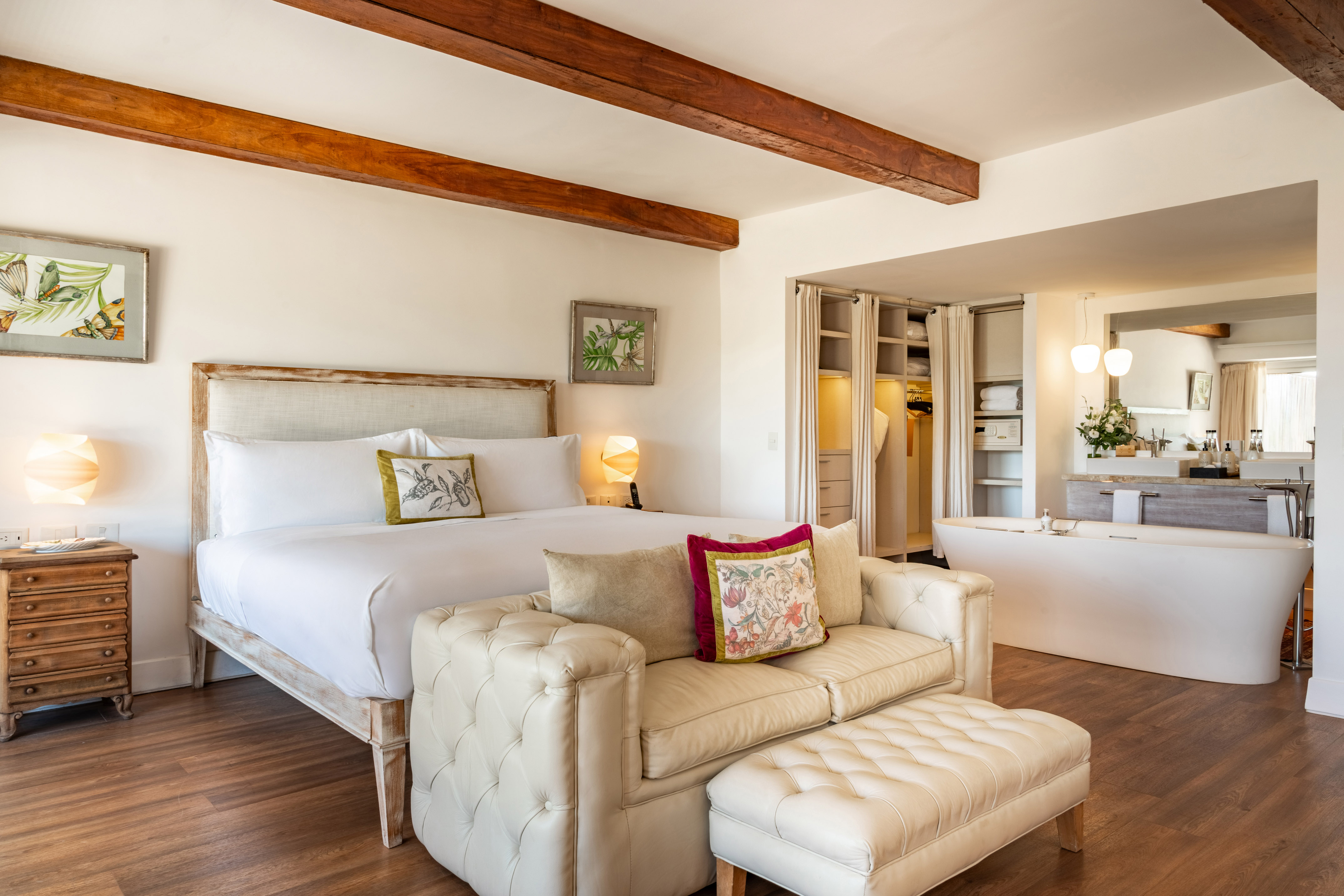 Modern luxury hotel suite with king bed, wooden beams, and freestanding soaking tub.